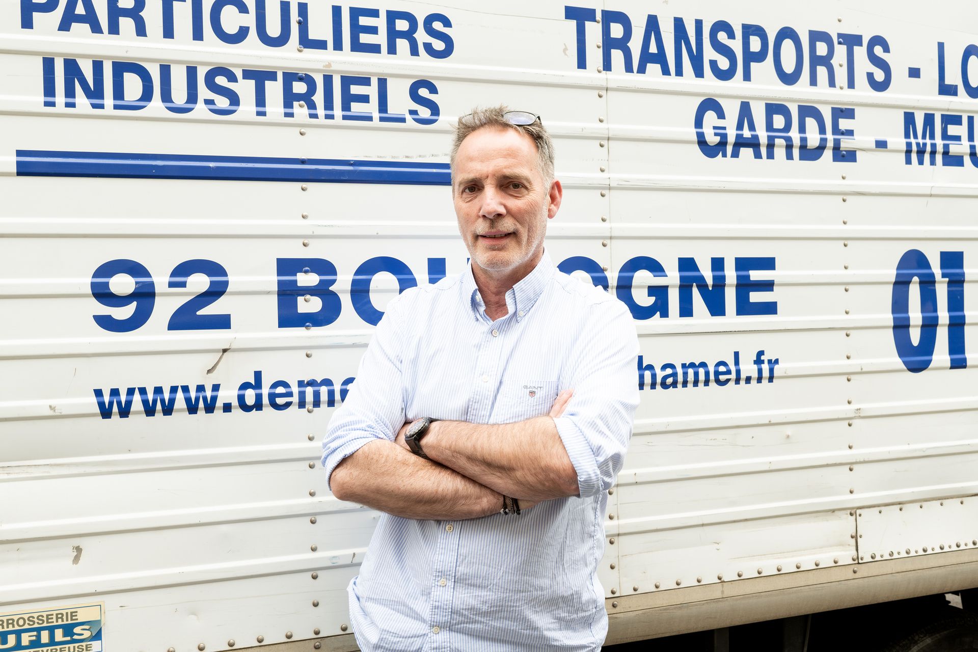 Patron de l'entreprise prenant la pose, souriant, devant son camion