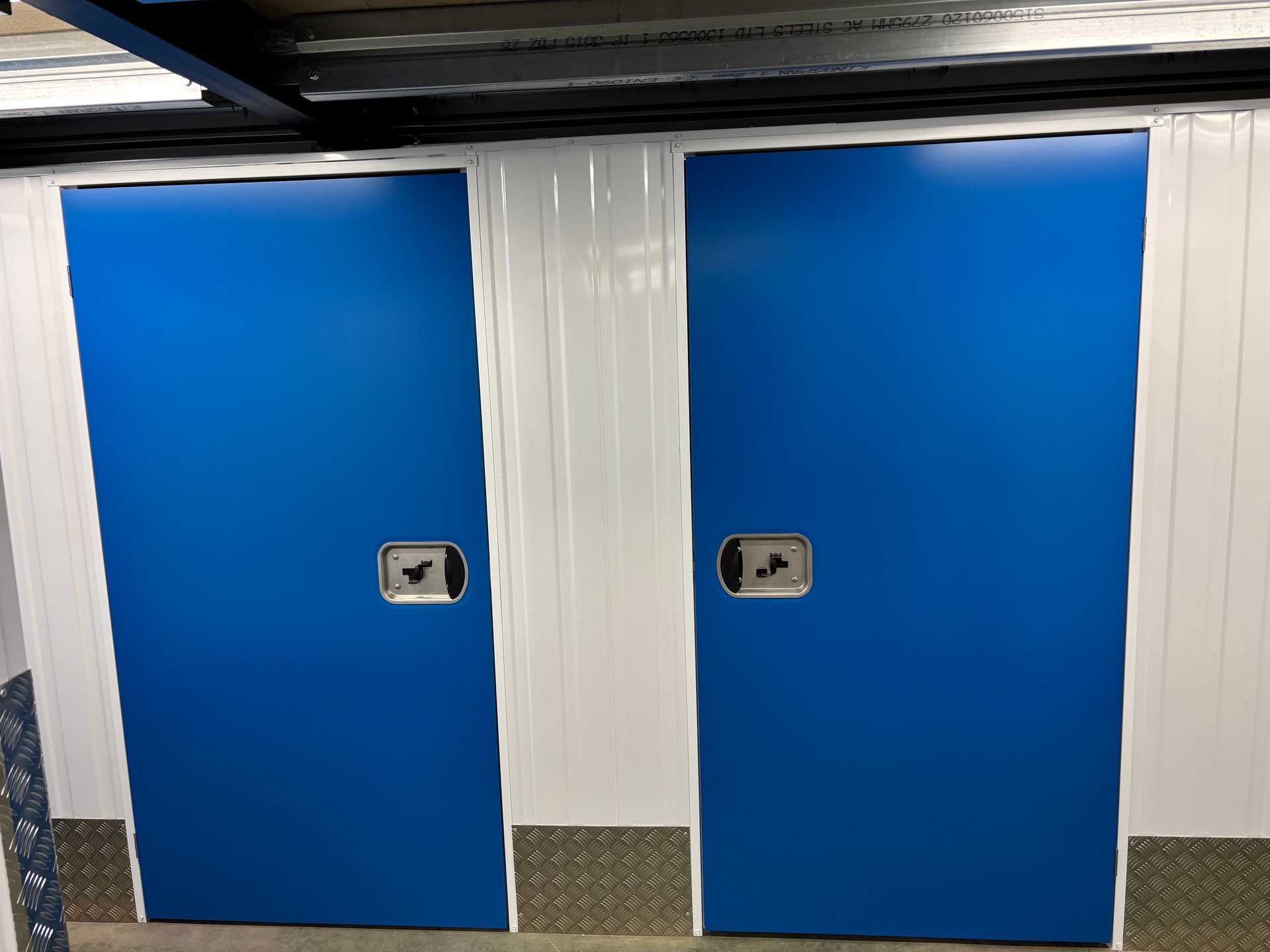 Deux portes bleues avec des serrures argentées, séparées par une cloison blanche.
