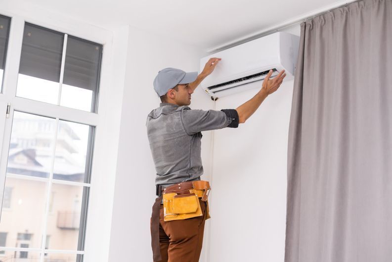 Un hombre está instalando un aire acondicionado en una sala de estar.