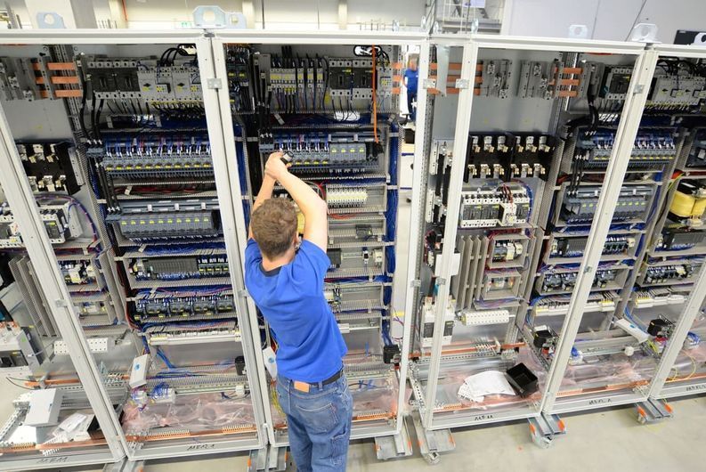 Un hombre está trabajando en un panel eléctrico en una fábrica.