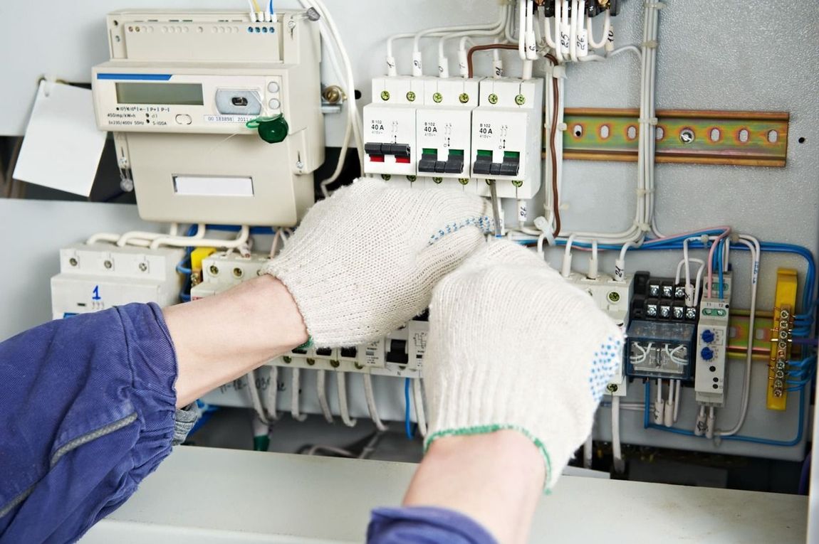 Una persona que lleva guantes está trabajando en una caja eléctrica.