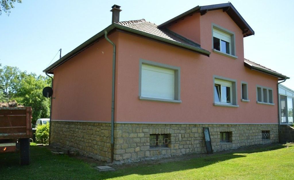 Une façade de maison rose avec de la pierre.