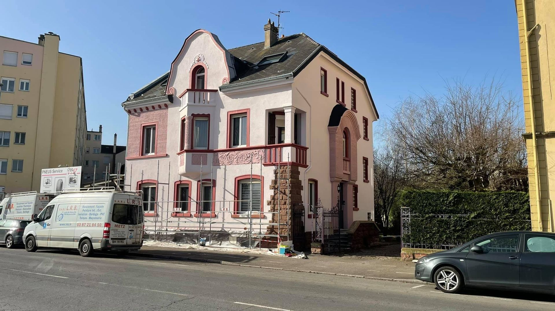 Un bâtiment rose avec un camion sur la gauche.
