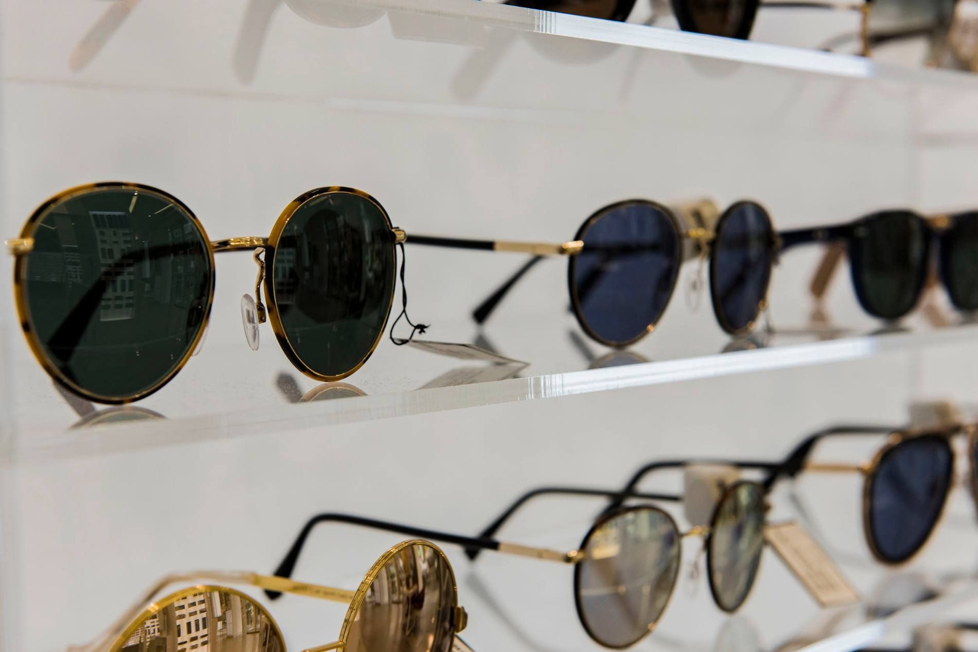 Una fila de gafas de sol colgadas en la pared de una tienda.