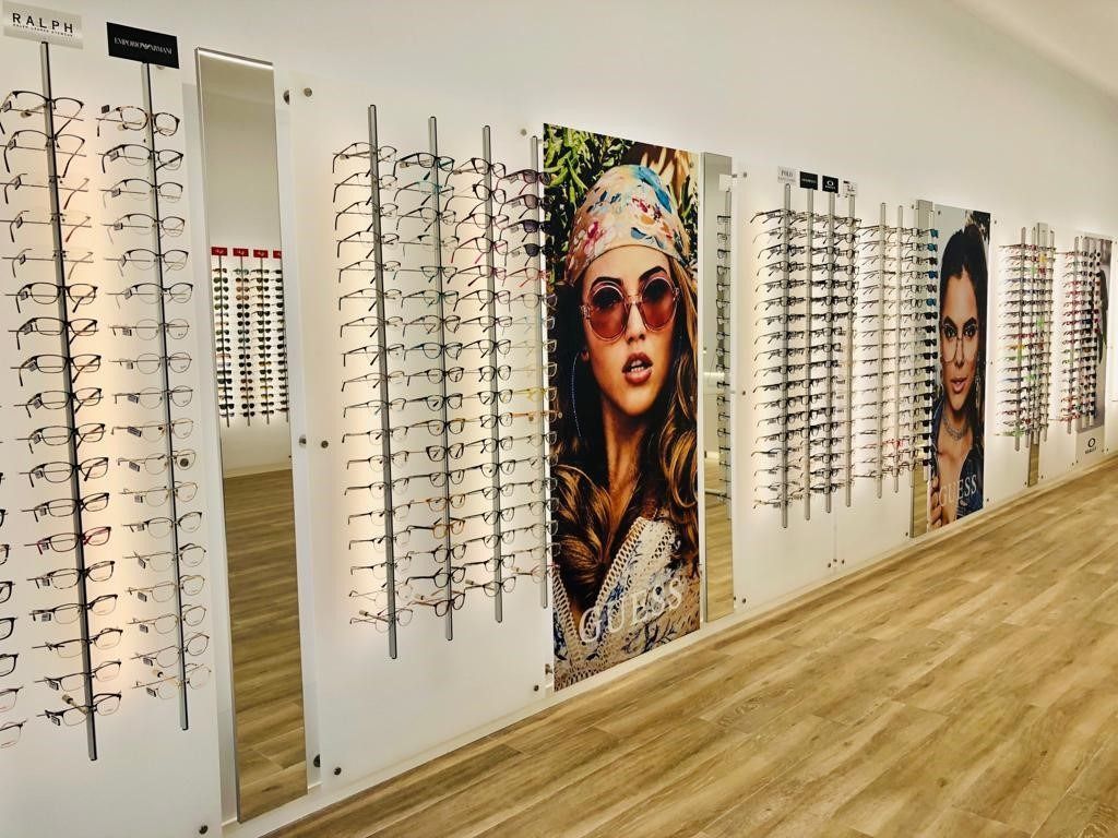 Una mujer que lleva gafas de sol está en una pared de una tienda de óptica.