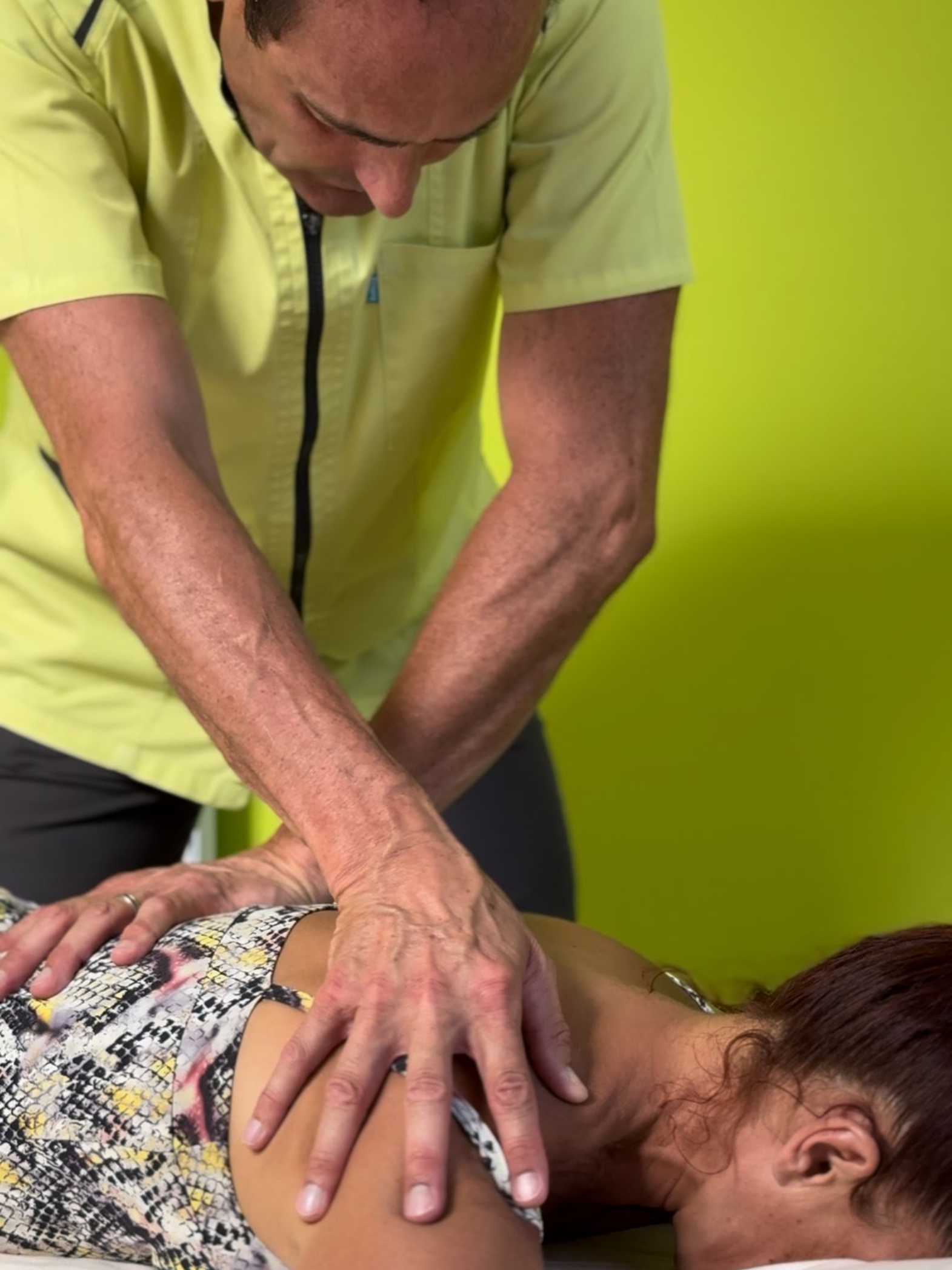 Un homme en chemise jaune donne un massage du dos.