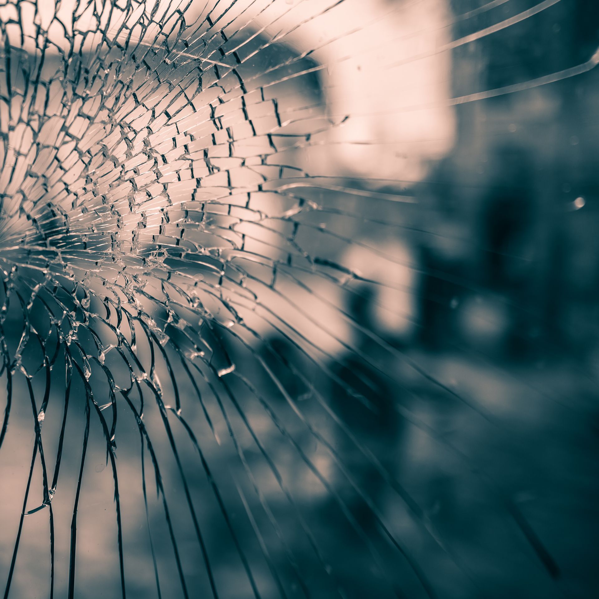 Gros plan sur du verre brisé présentant une fracture radiale sur un fond sombre et flou.