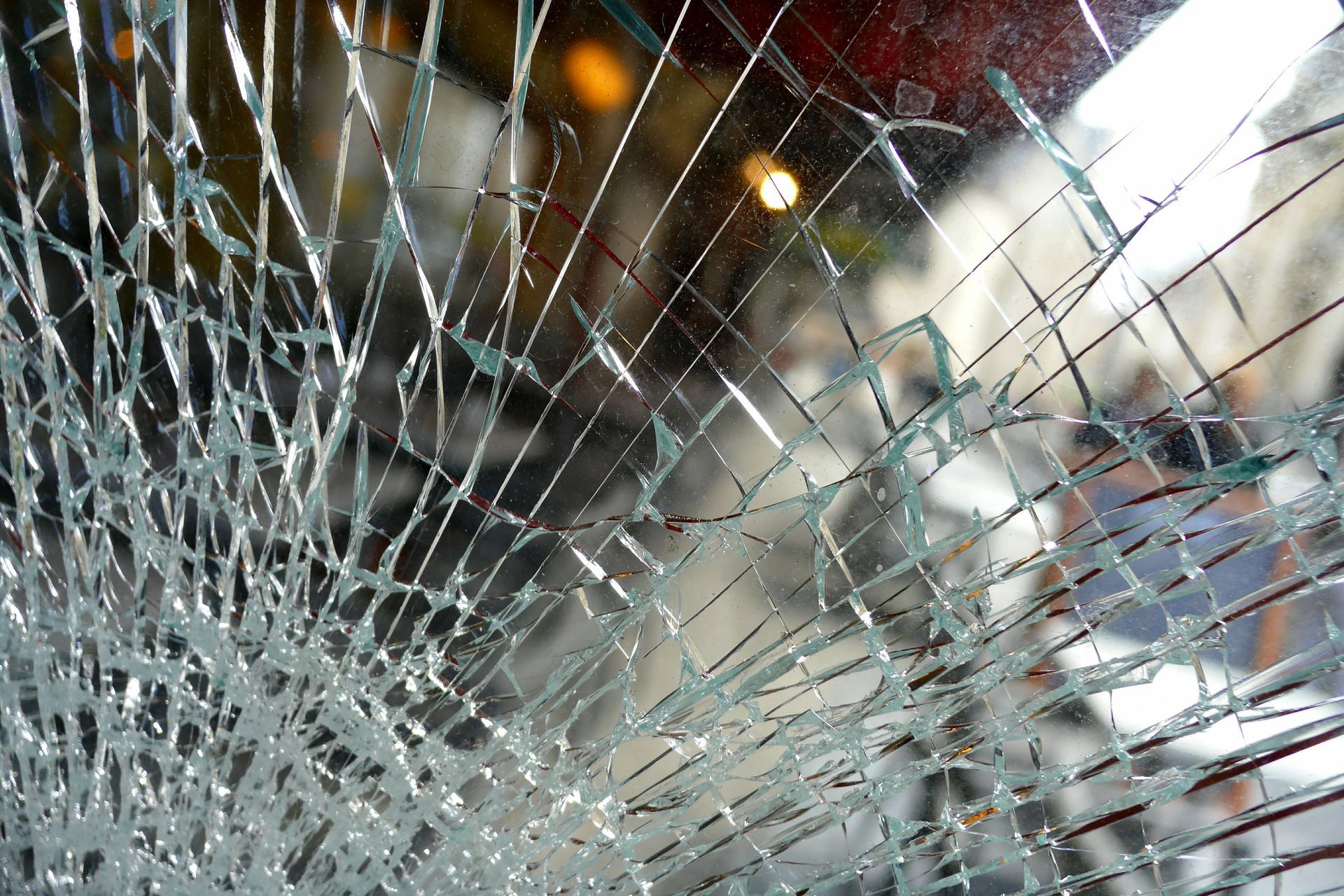 Gros plan sur une grande vitre trempée recouverte d'un réseau complexe et dense de fissures et de fractures.