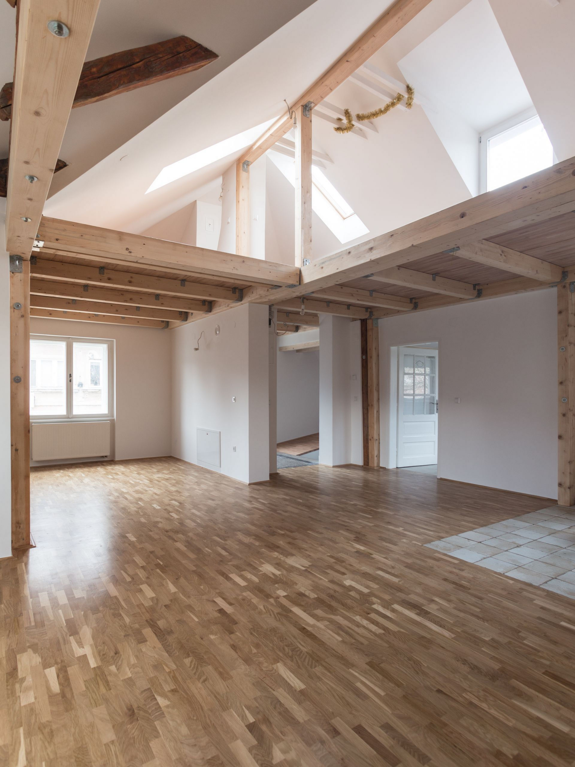 Intérieur spacieux avec poutres apparentes, parquet et lumière naturelle.