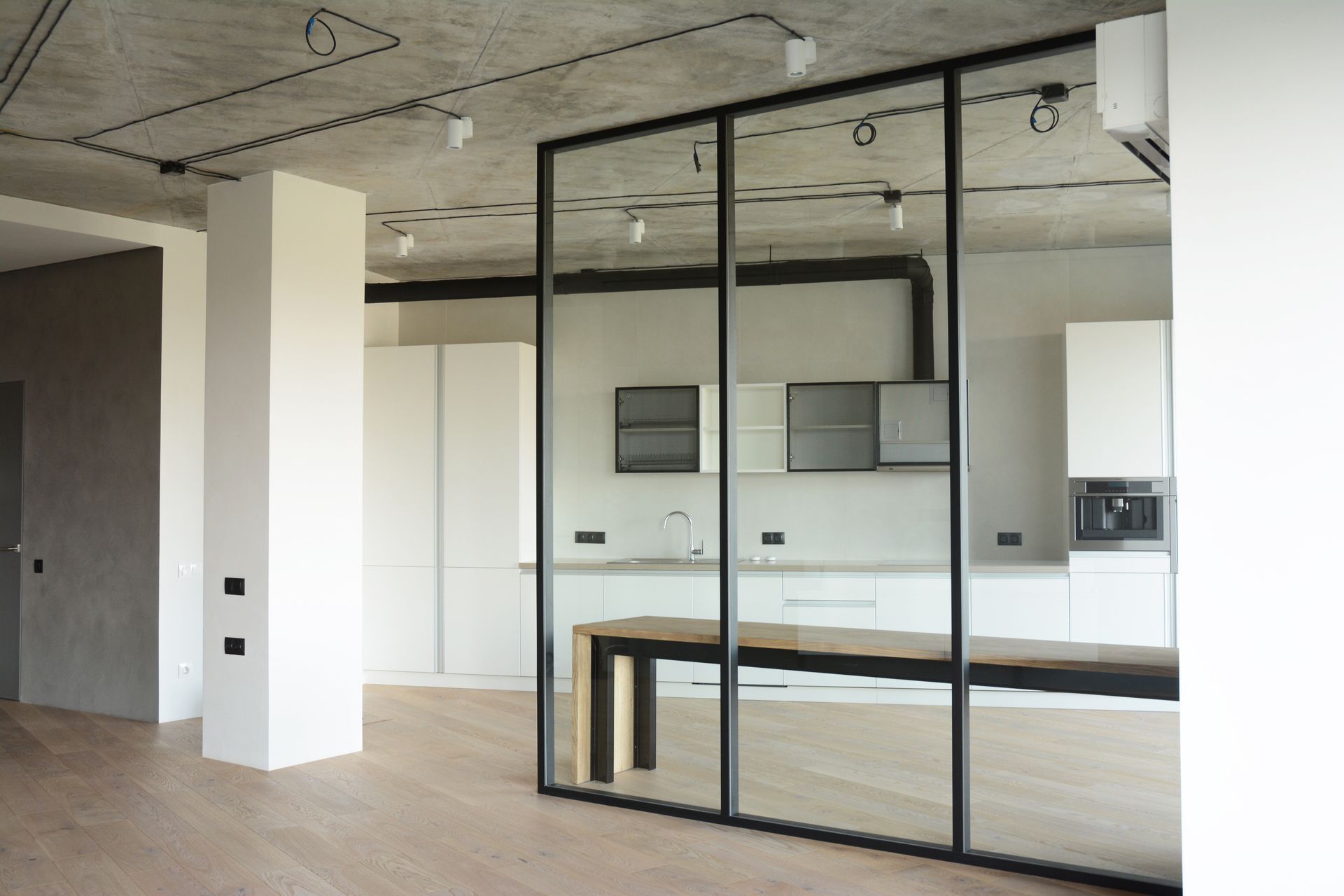 Cuisine moderne avec cloison vitrée et placards blancs, design minimaliste, table en bois.
