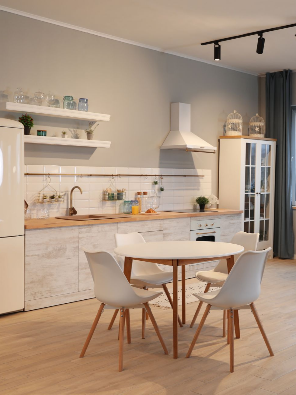 Intérieur de la cuisine avec un réfrigérateur blanc, des placards et une table ronde avec quatre chaises.
