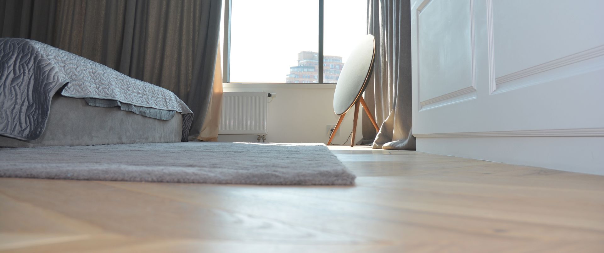 Une chambre avec un lit, un tapis, une fenêtre et un miroir.