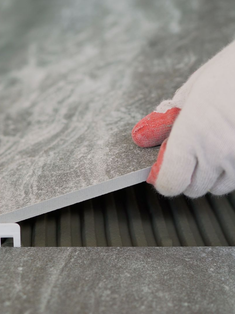 Main plaçant un carreau sur une agrafe de nivellement pour la pose.