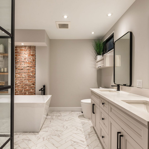 Salle de bains moderne avec baignoire blanche, meuble de lavabo et sol en carrelage à chevrons.