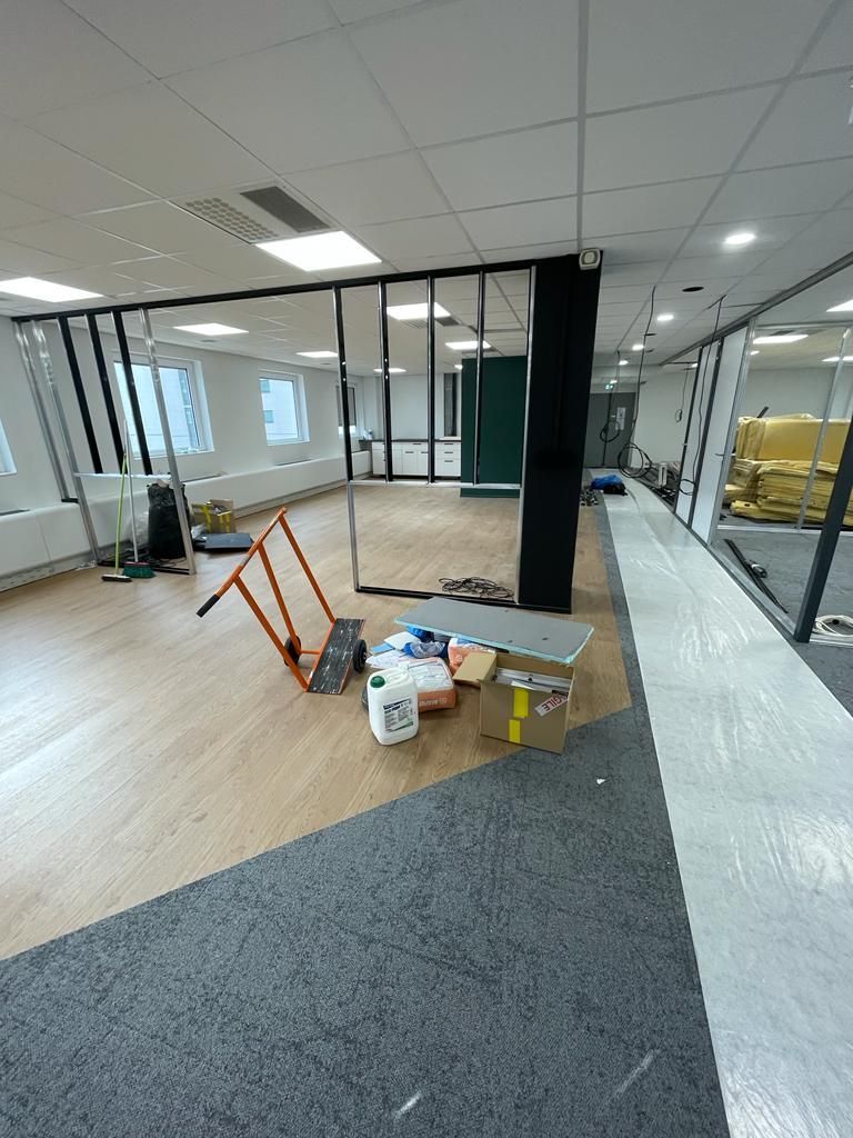 Espace de bureaux avec parquet et moquette, cloisons vitrées et matériaux de construction.