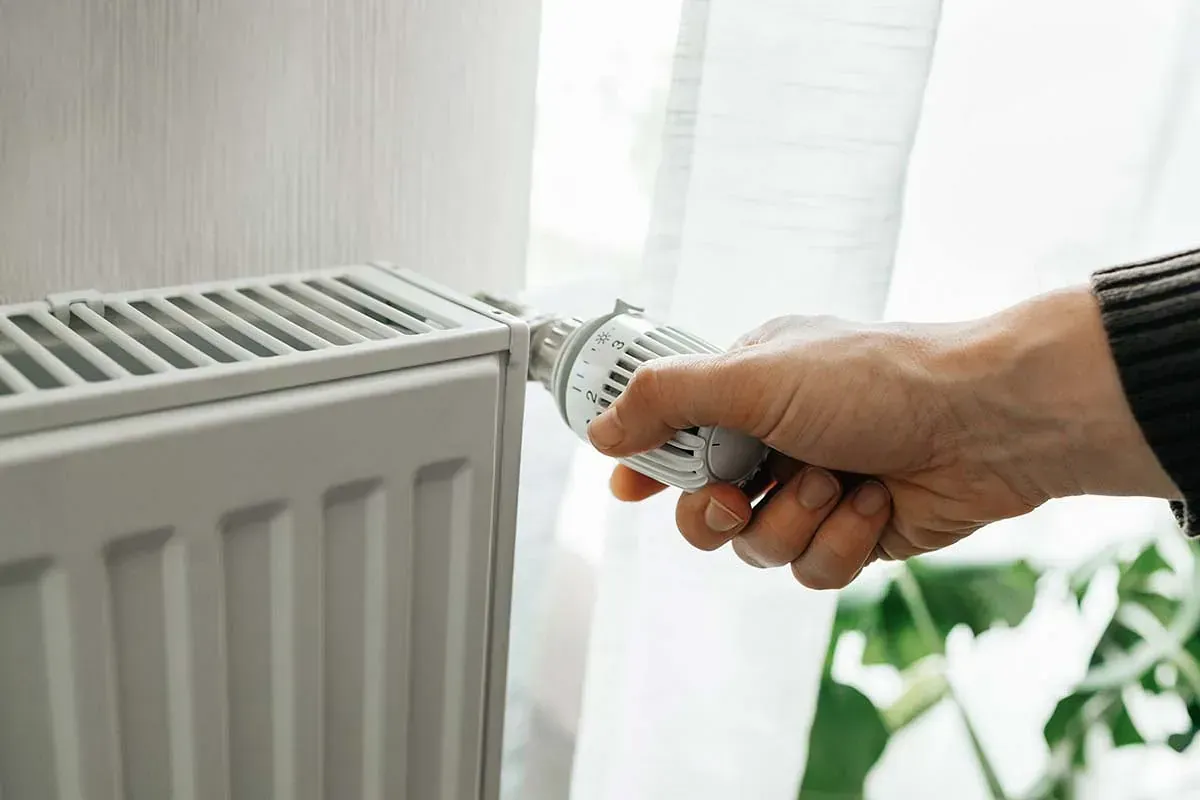 Una persona está ajustando un termostato en un radiador.