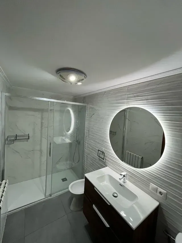 Un baño con lavabo, inodoro, ducha y espejo.
