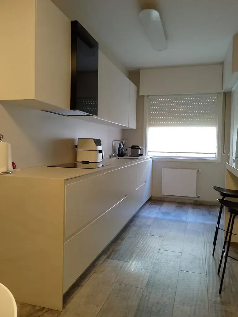 Una cocina larga con gabinetes blancos y una ventana.