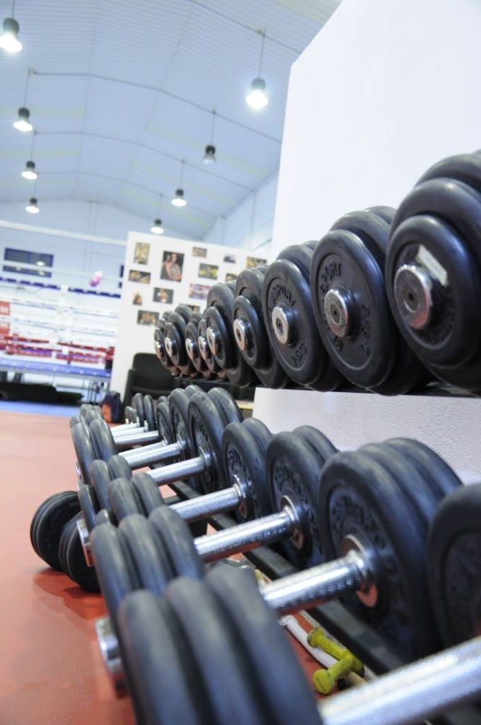 Mancuernas en un rack en un gimnasio con suelo rojo.