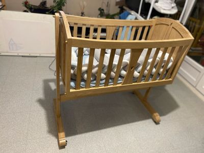 Berceau en bois pour bébé sur pied, dans une pièce au sol clair.