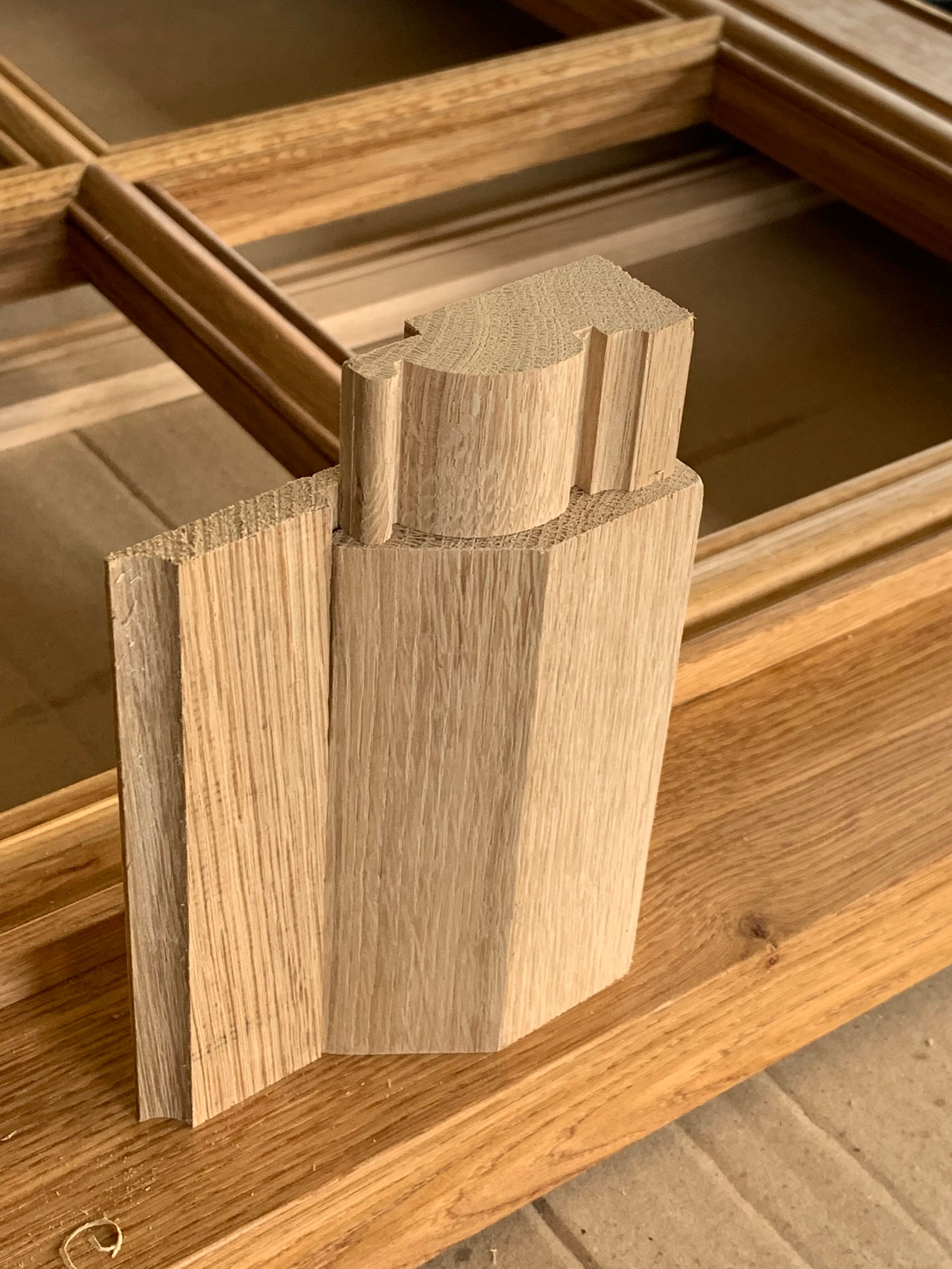 Pièces d’assemblage en bois ajustées sur une table, montrant un assemblage à queues droites au niveau d’un angle en bois.