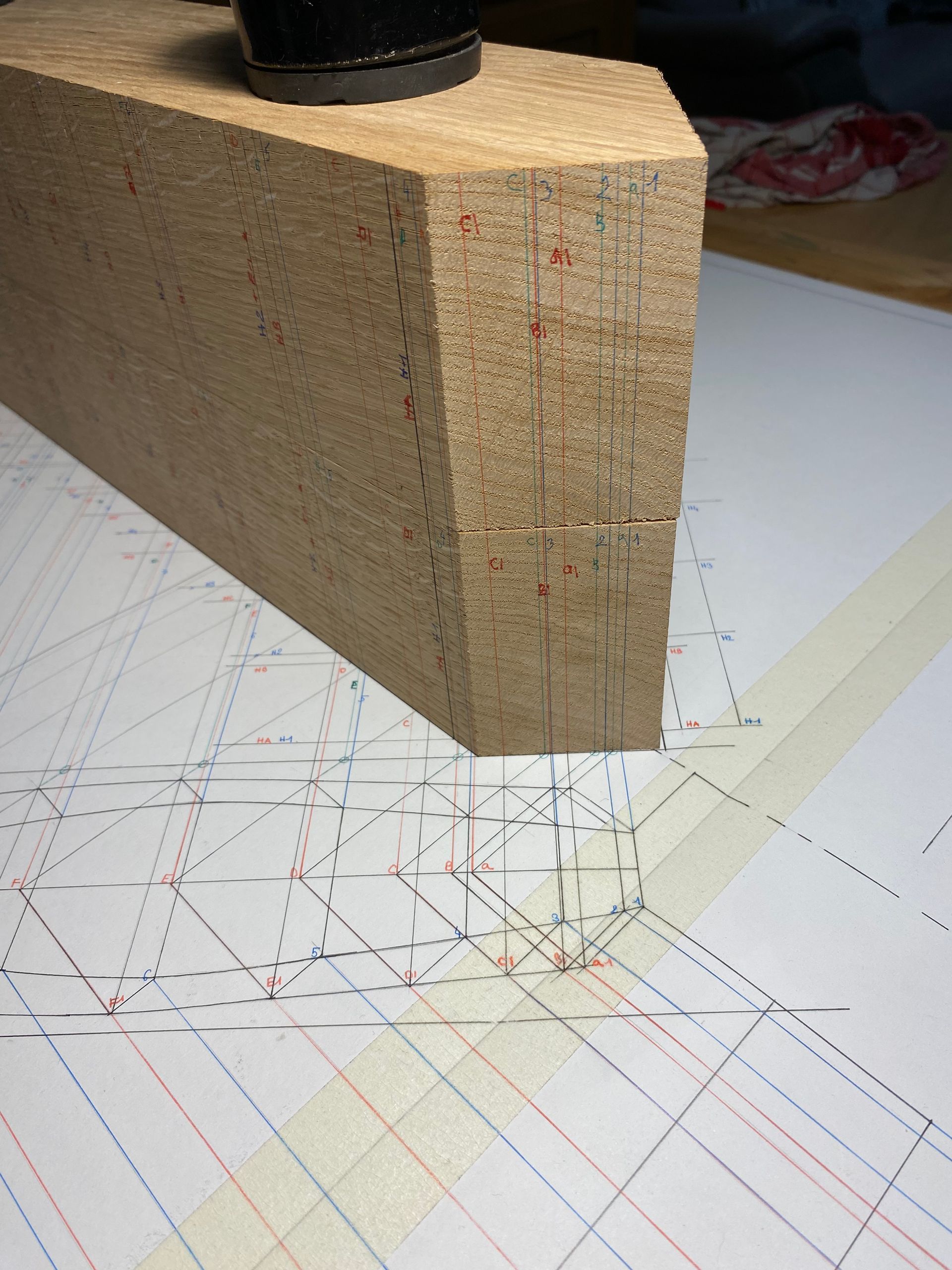 Bloc de bois sur du papier à motifs, avec des lignes diagonales tracées au crayon.