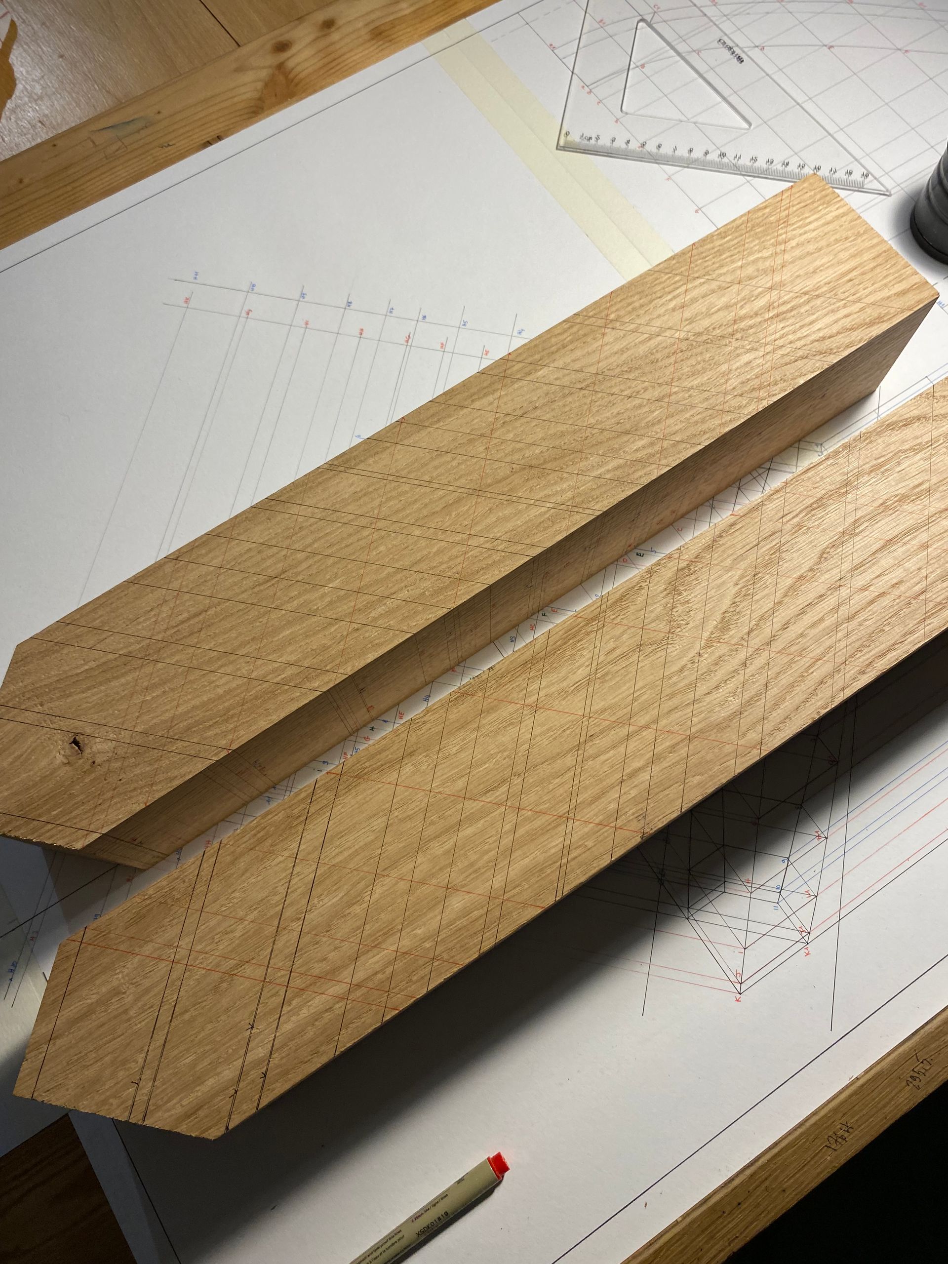 Deux cales en bois sur une table à dessin, avec des croquis au crayon et une règle en dessous.