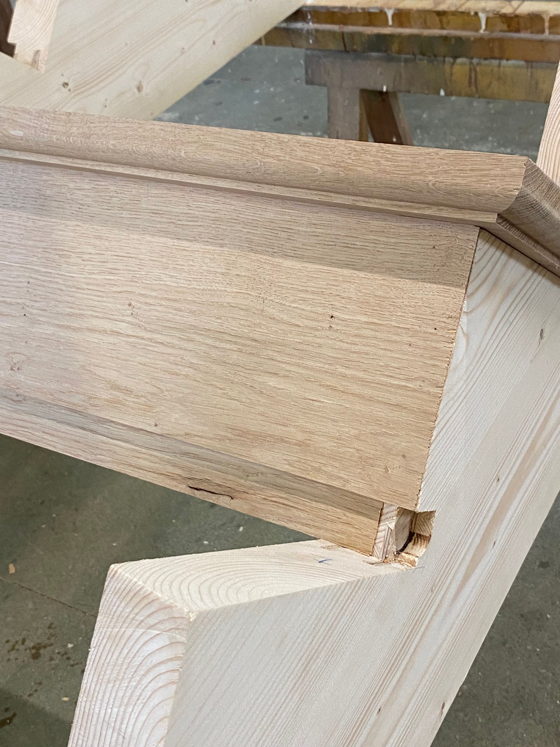 Gros plan sur une marche d’escalier en bois en cours d’installation dans la structure de l’escalier, avec une encoche visible et un veinage du bois brut.