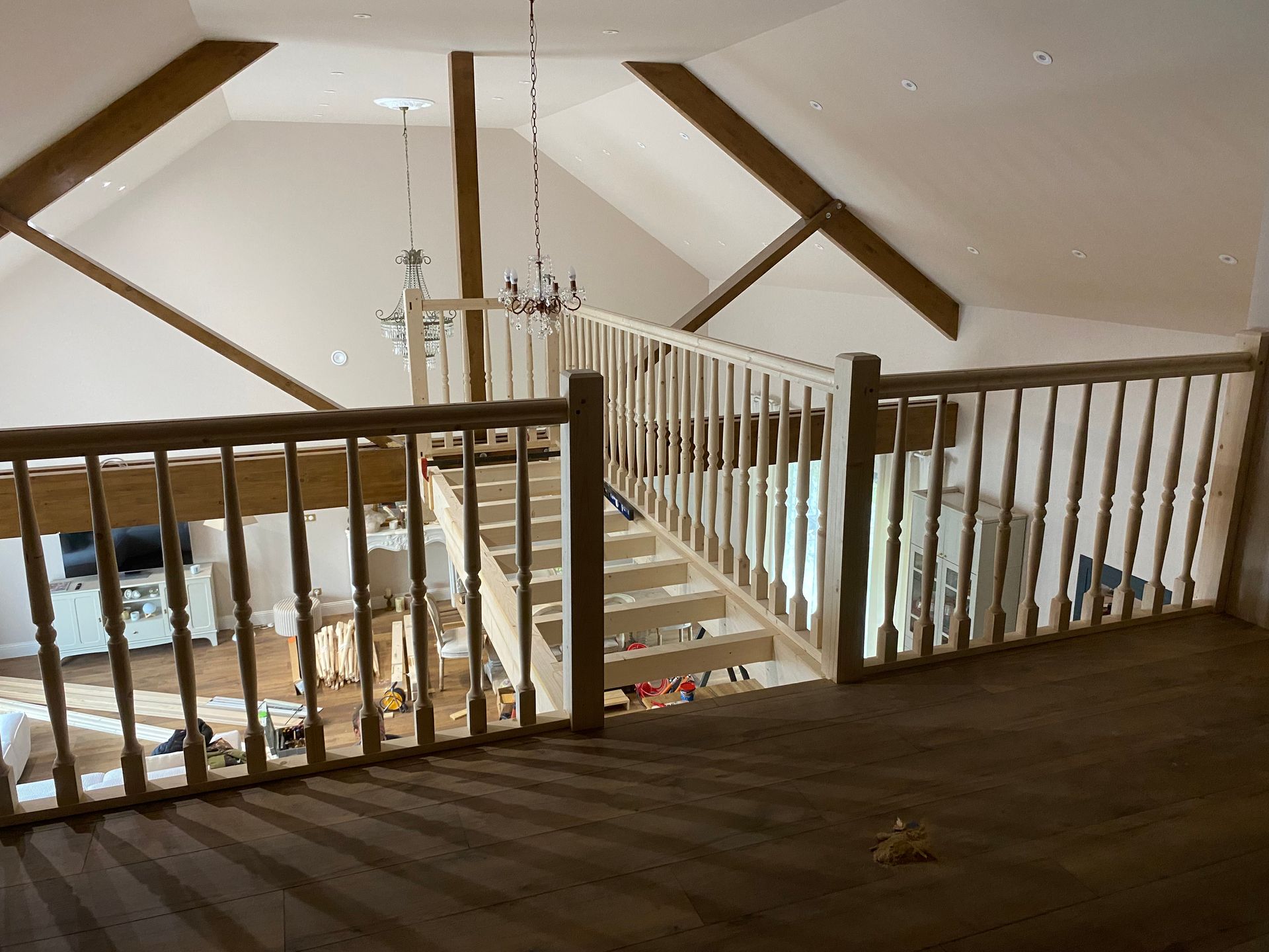Intérieur de loft avec des rampes en bois, un escalier et un lustre sous un plafond en pente.