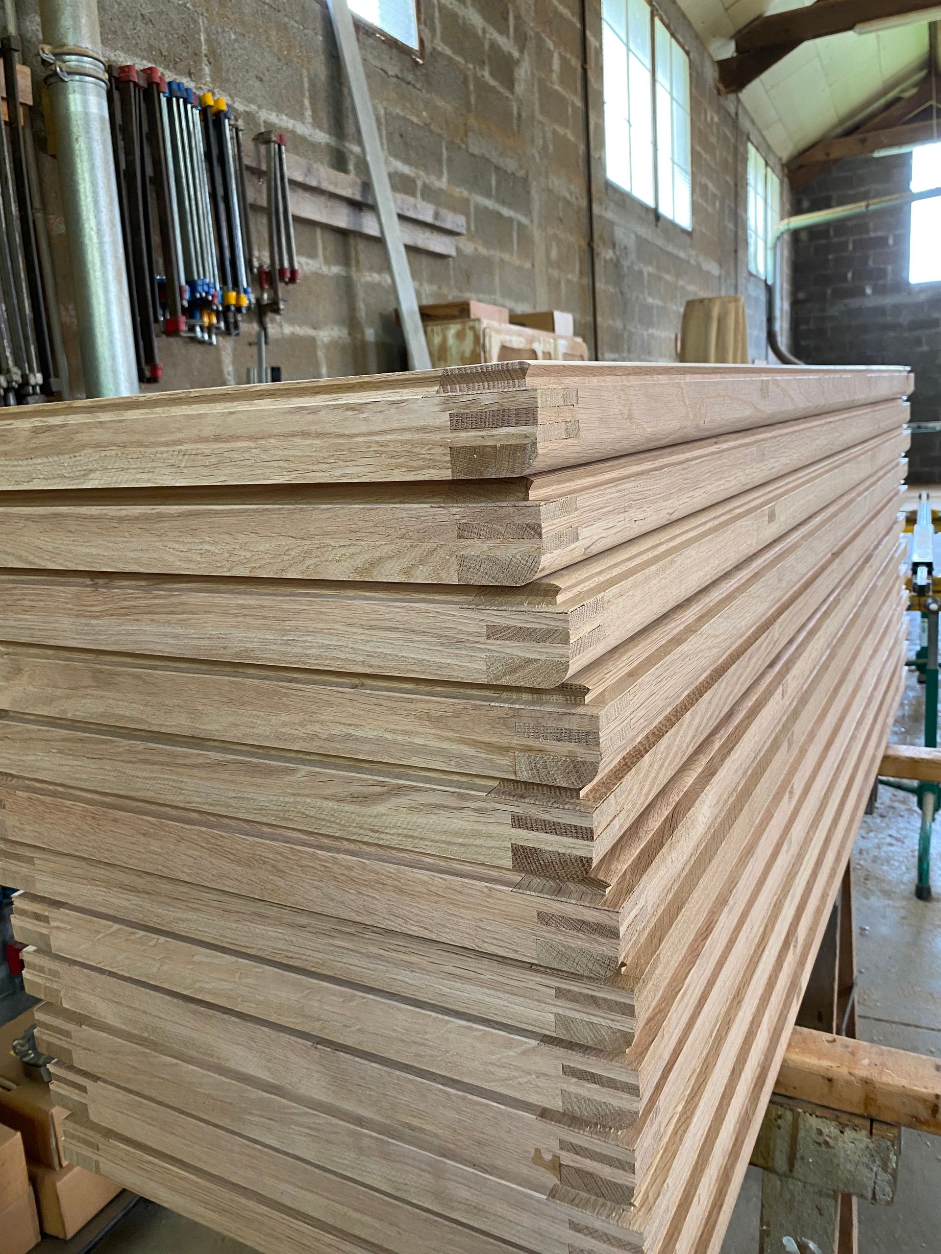 Pile de fenêtres en bois sur un établi dans un atelier industriel.