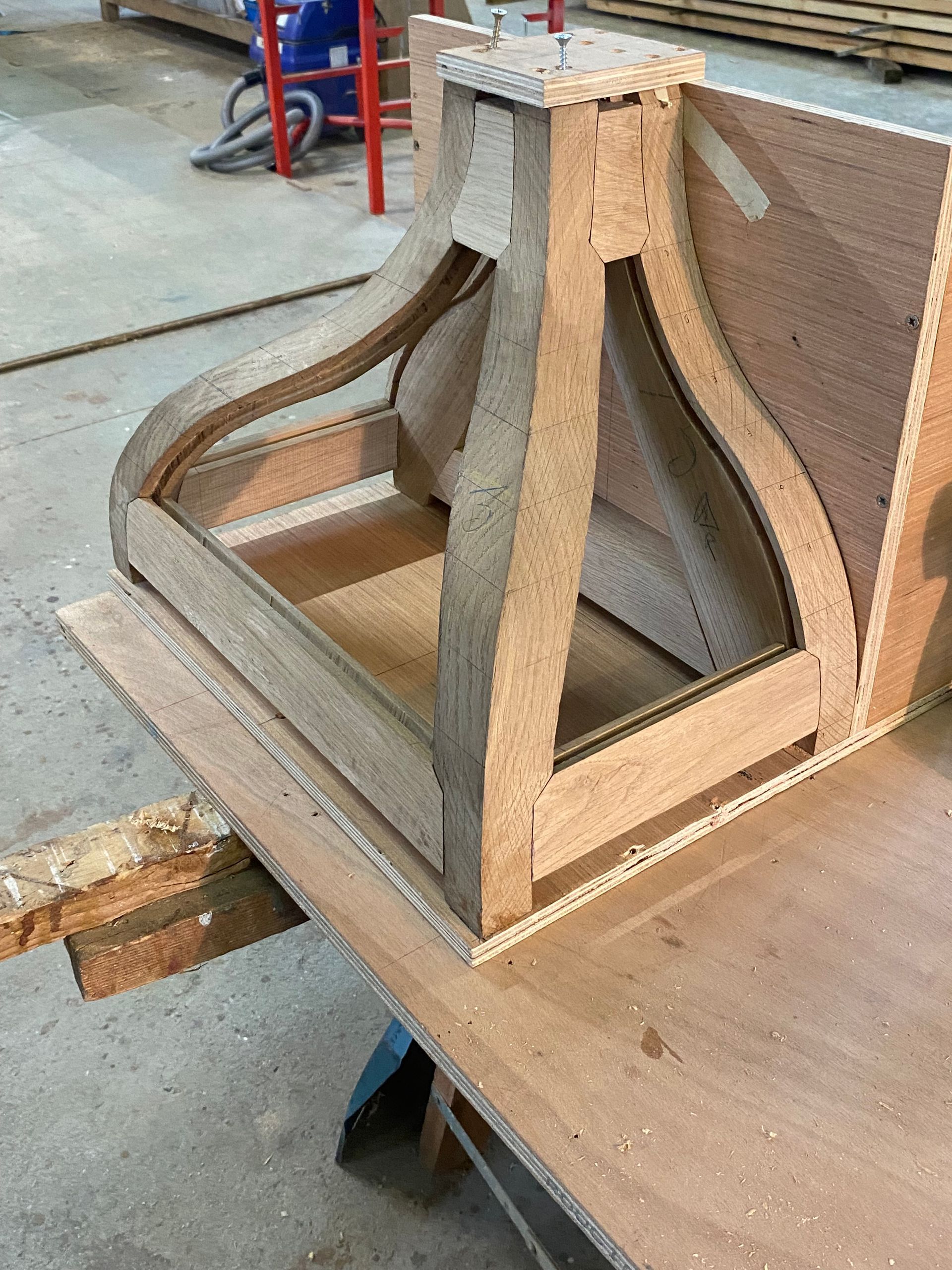 Ossature en bois avec des supports incurvés sur le sol d’un atelier, vue de dessus.