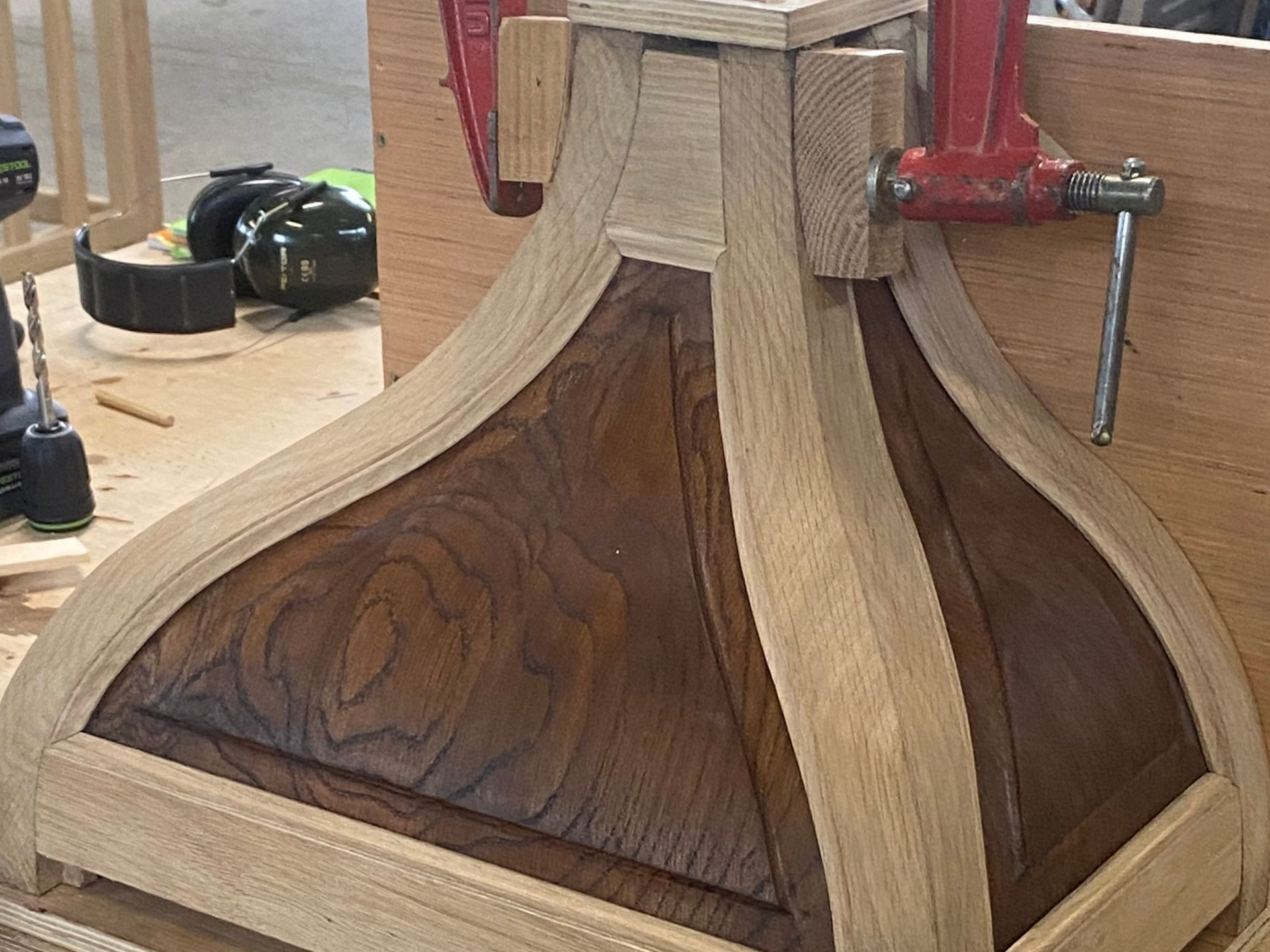 Support décoratif en bois serré dans un atelier, avec des panneaux courbés aux veinures claires et foncées.