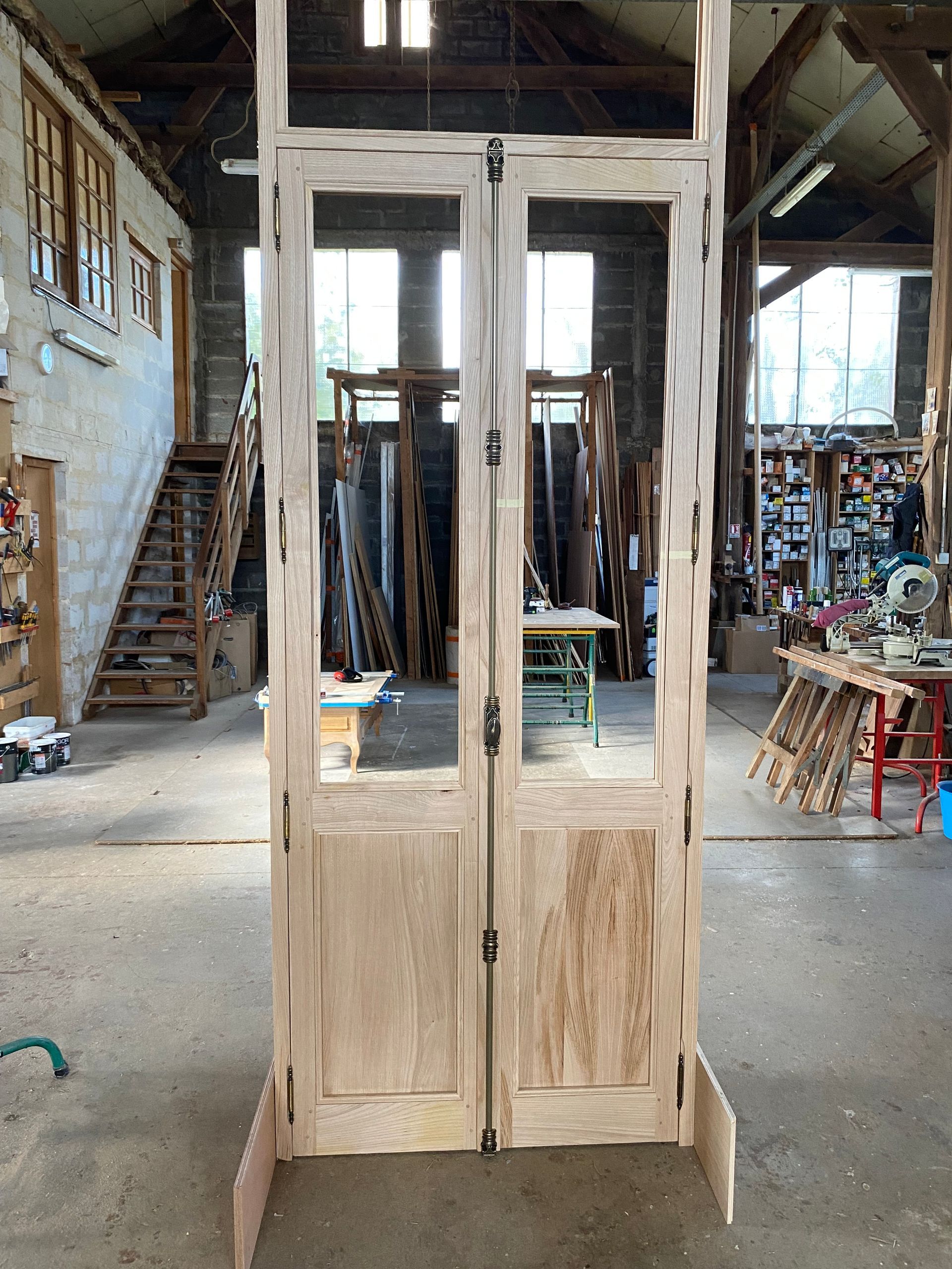 Grand armoire en bois brut avec portes vitrées, dans un atelier ou un entrepôt.
