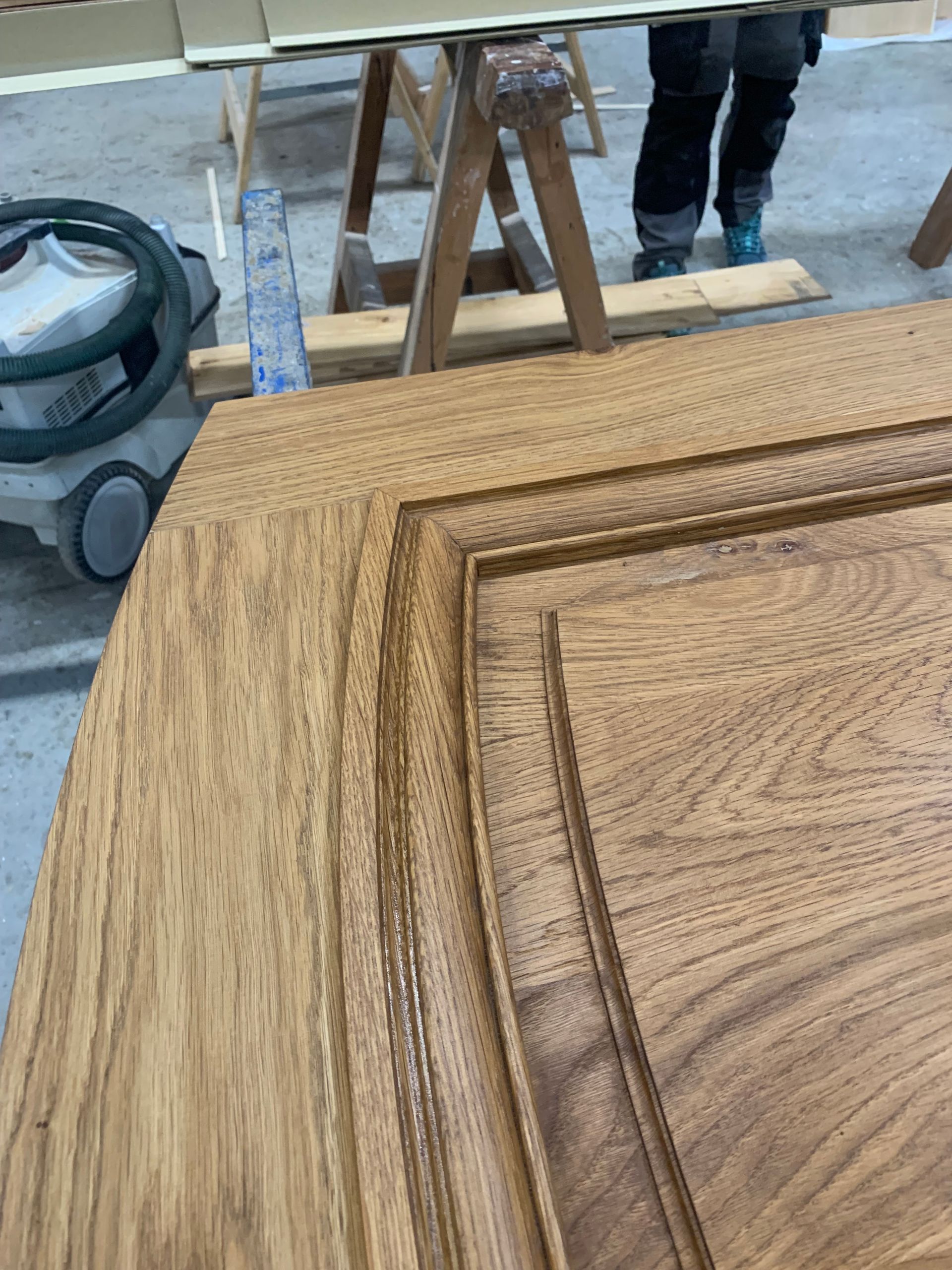 Gros plan sur une porte de meuble en bois ornée d’incrustations, dans un atelier.