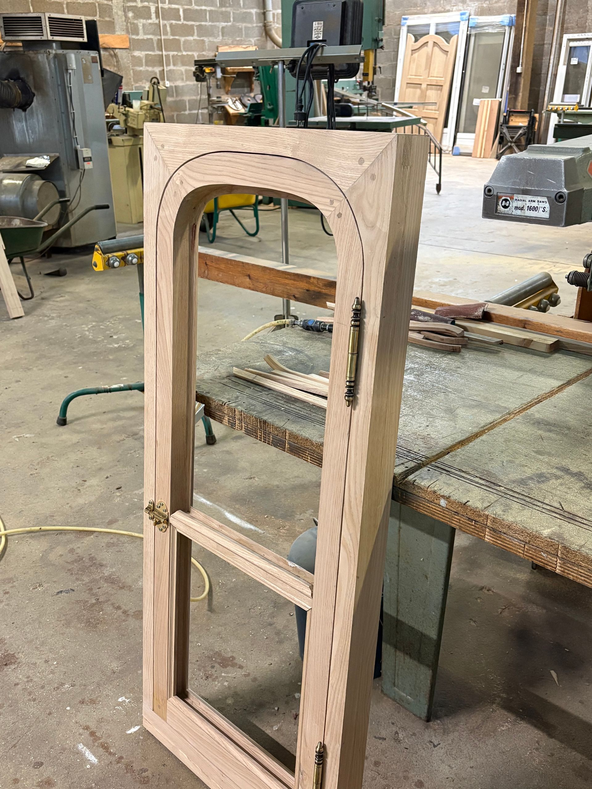 Cadre de fenêtre en bois, debout dans un atelier à côté d’un établi.