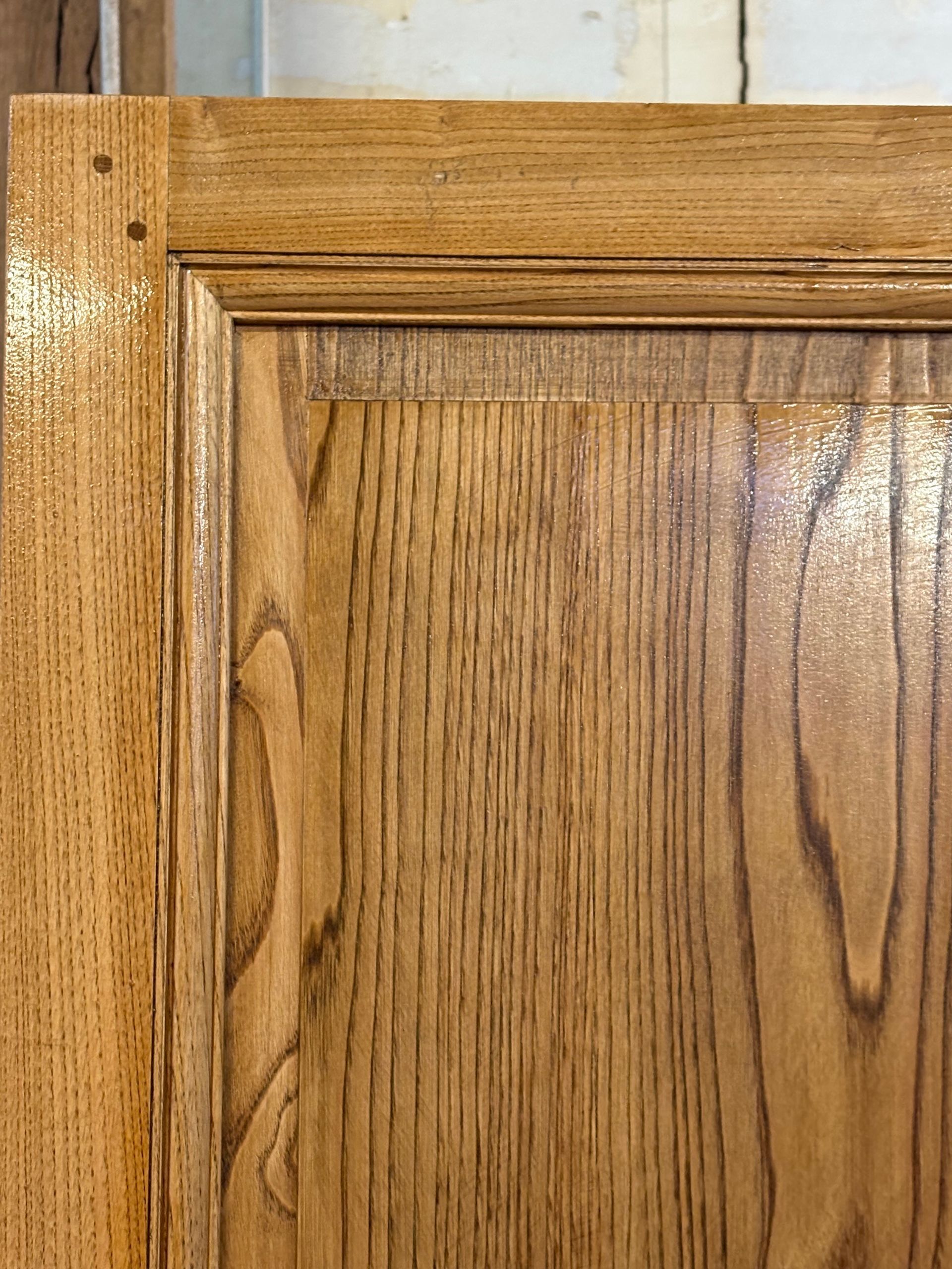Gros plan d’une porte de placard en bois, avec un cadre en chêne clair et des panneaux en bois plus foncé.