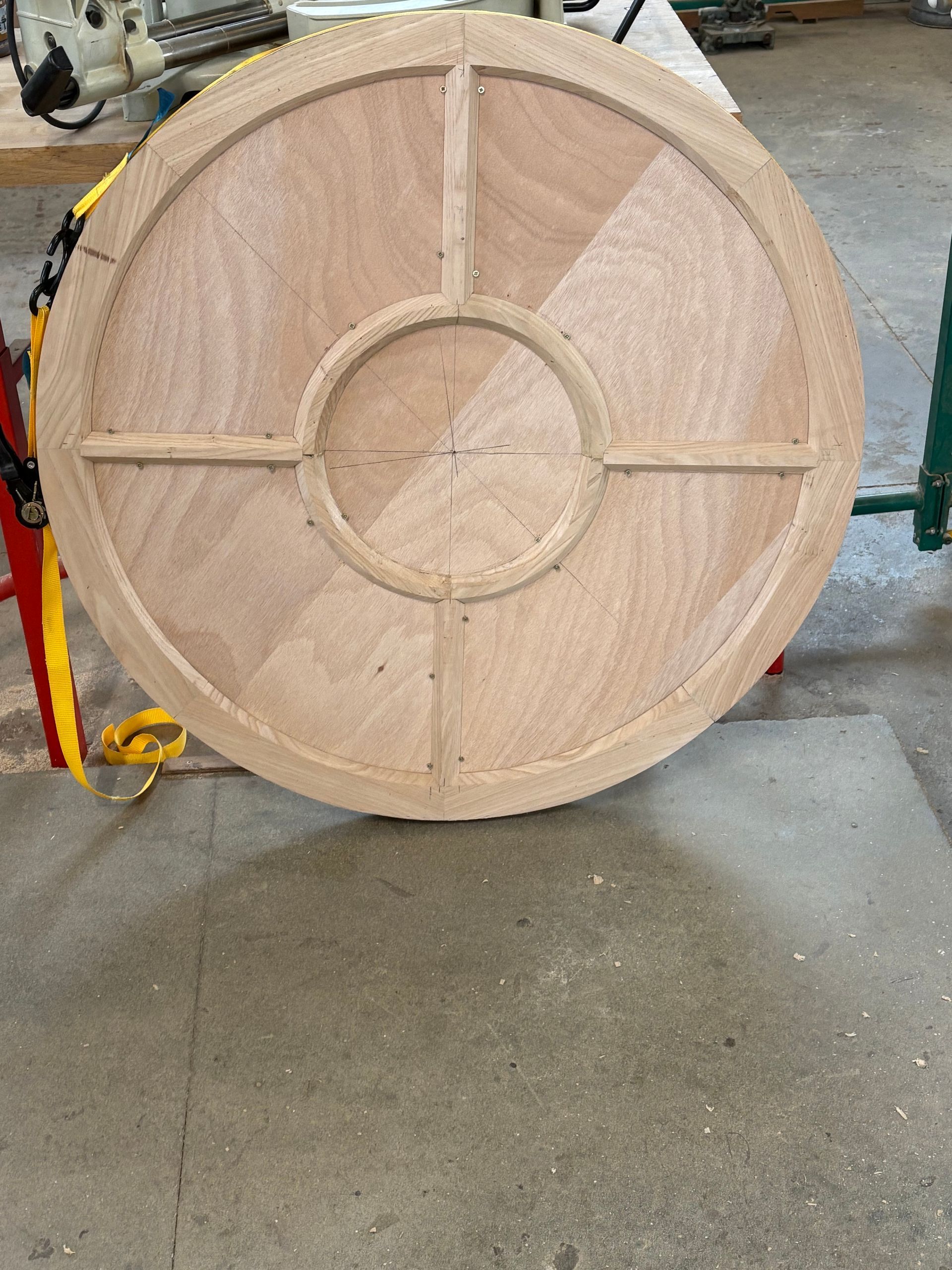 Roue en bois avec une corde, vue de face sur un sol en béton.