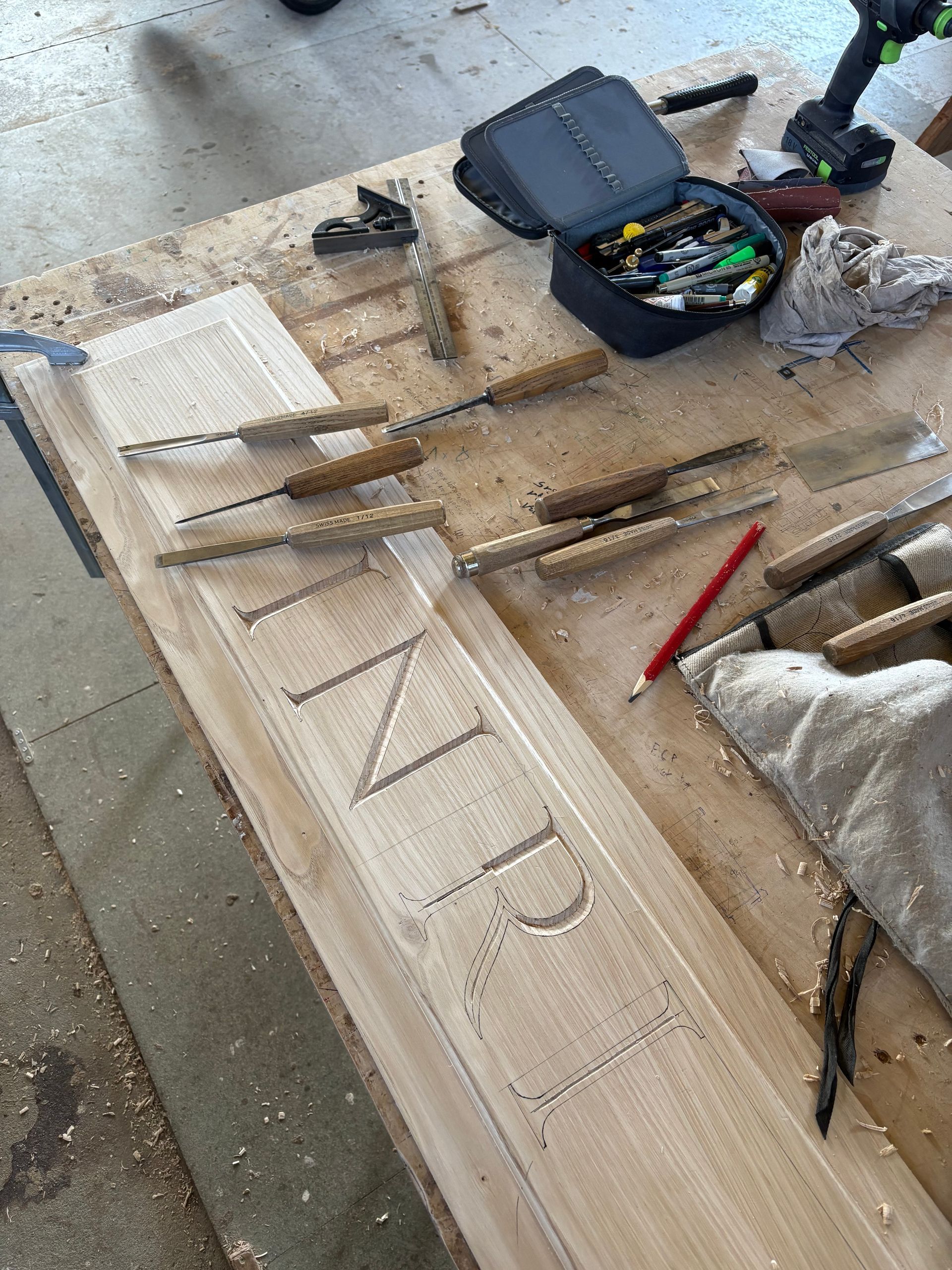 Outils de menuiserie et enseigne en bois sculptée à la main en cours de réalisation sur un établi.