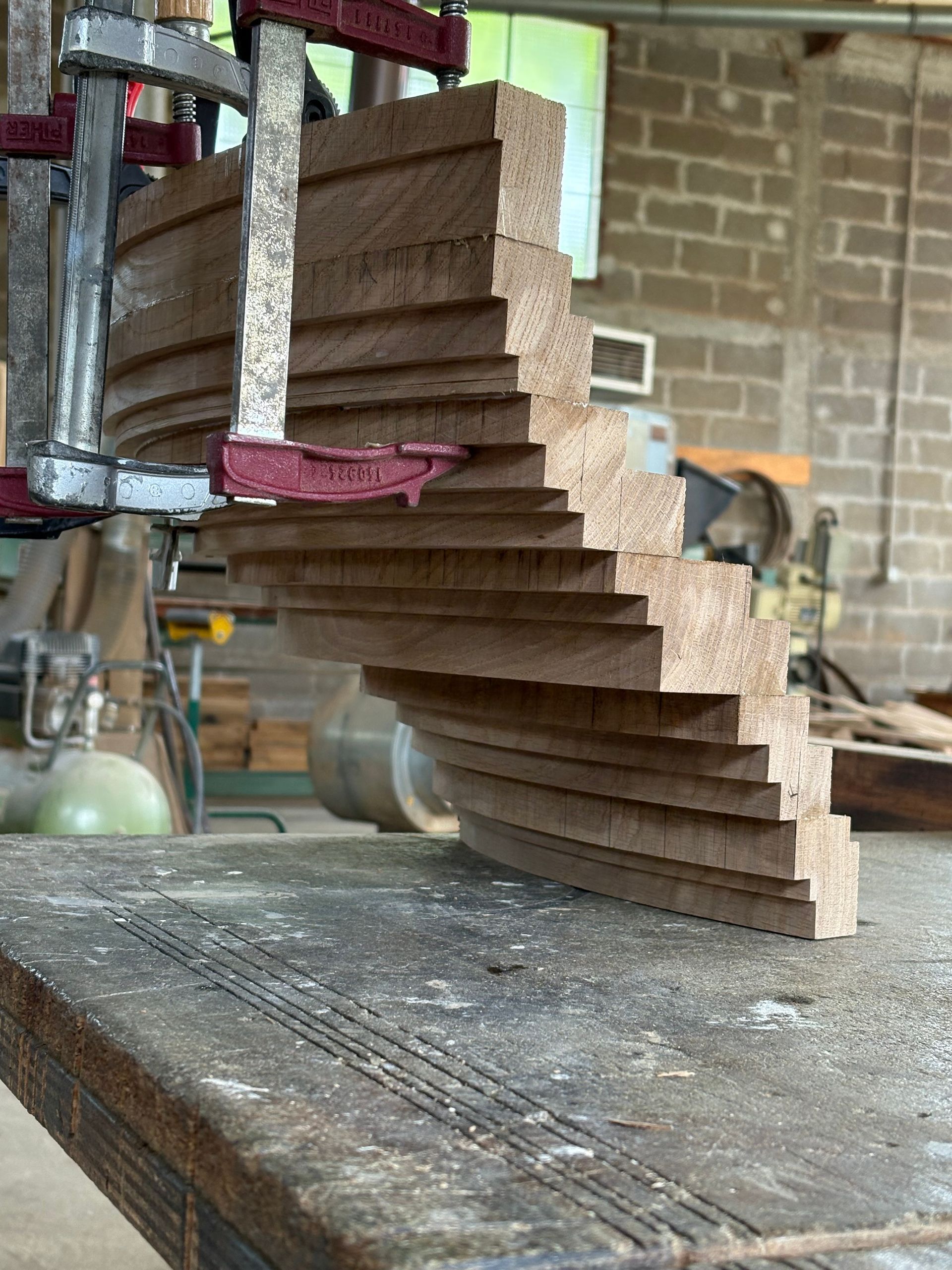 Pile de bois comprimée par un serre-joint sur un établi d’atelier.