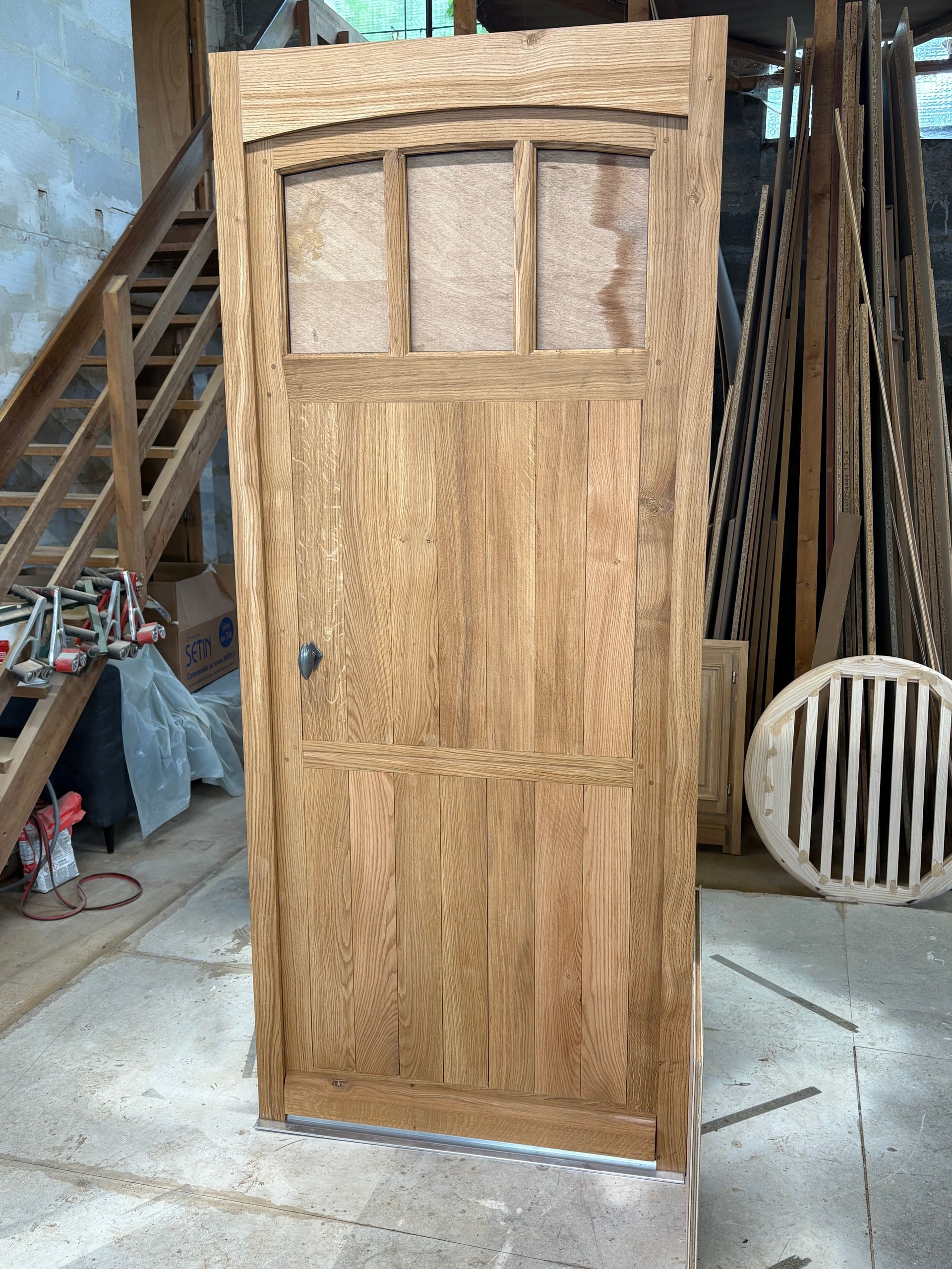 Porte en bois avec de petits carreaux de vitre, dans un atelier ou sur un chantier.
