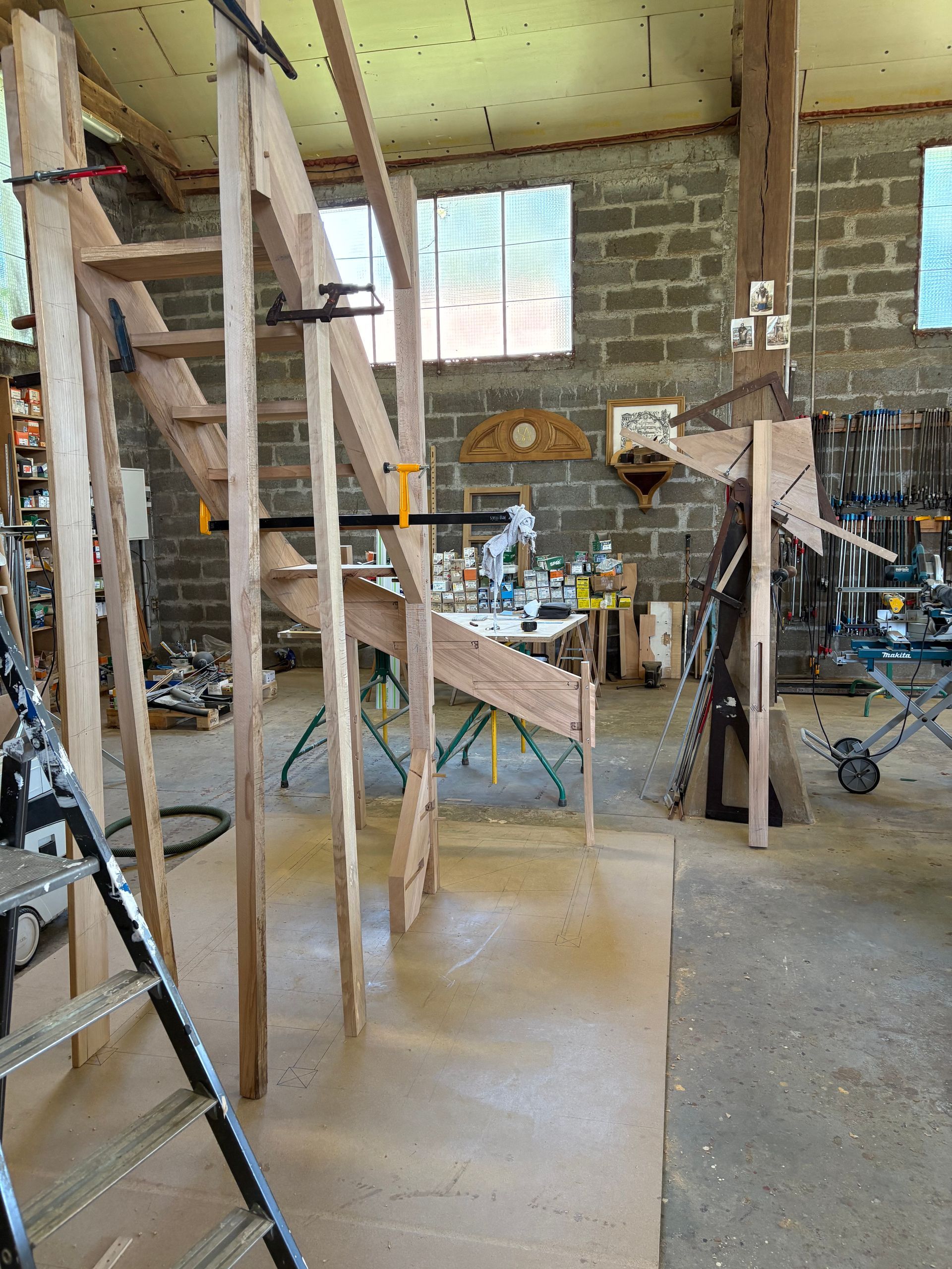 Intérieur d’atelier rustique en cours de rénovation, avec échafaudages en bois, outils et matériel.