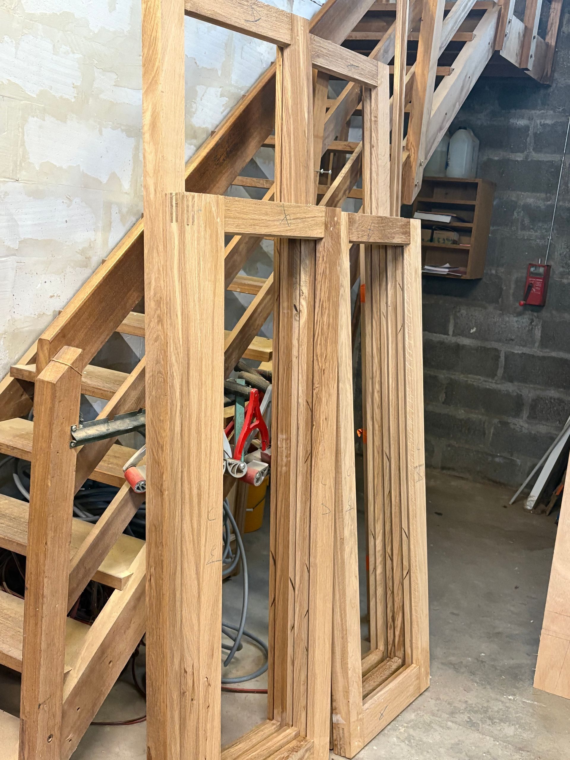 Structure d’escalier en bois et montants muraux dans un sous-sol en cours de rénovation.