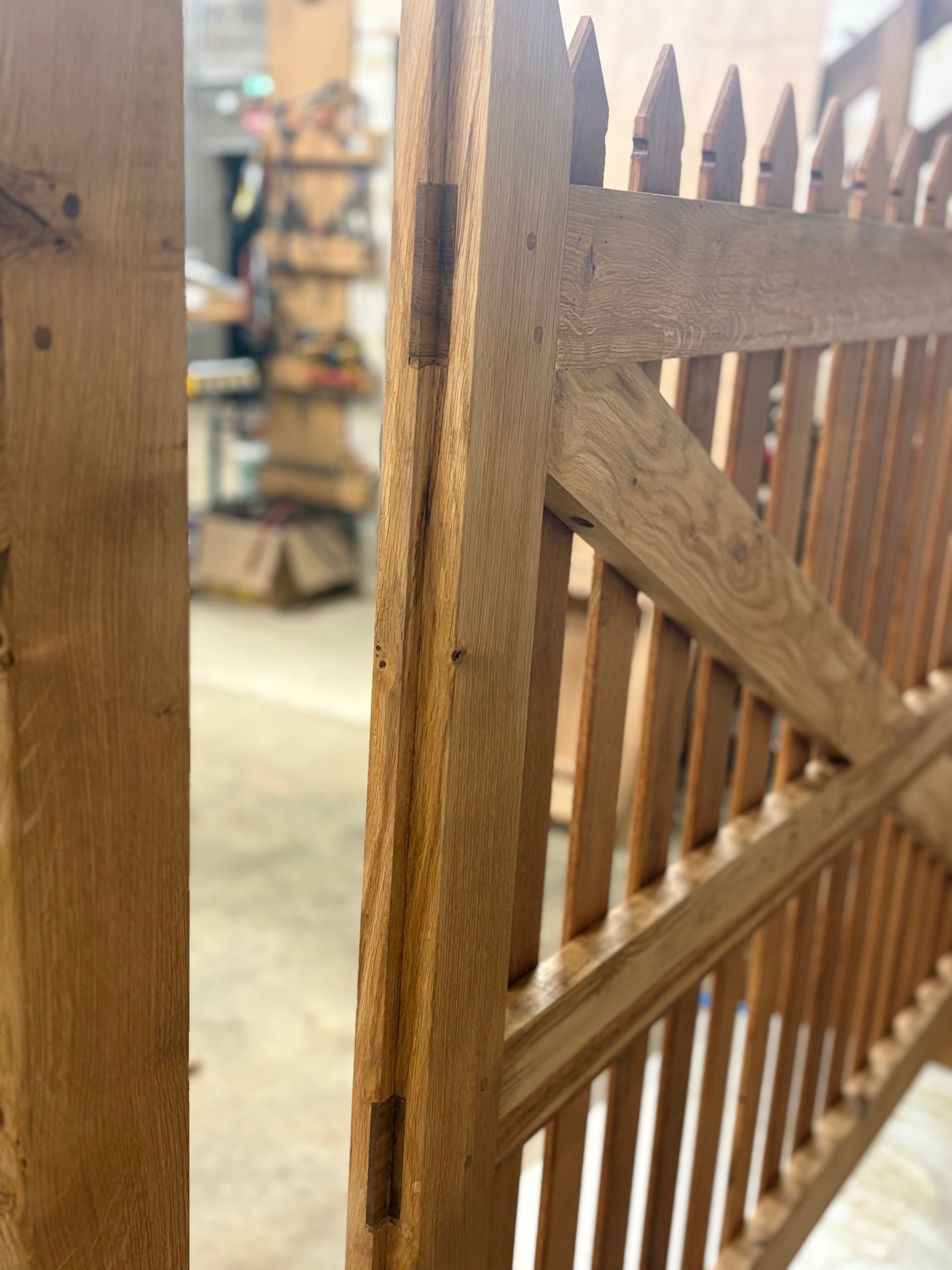 Gros plan d’un portail en bois composé de lattes pointues et de traverses diagonales, dans un atelier.