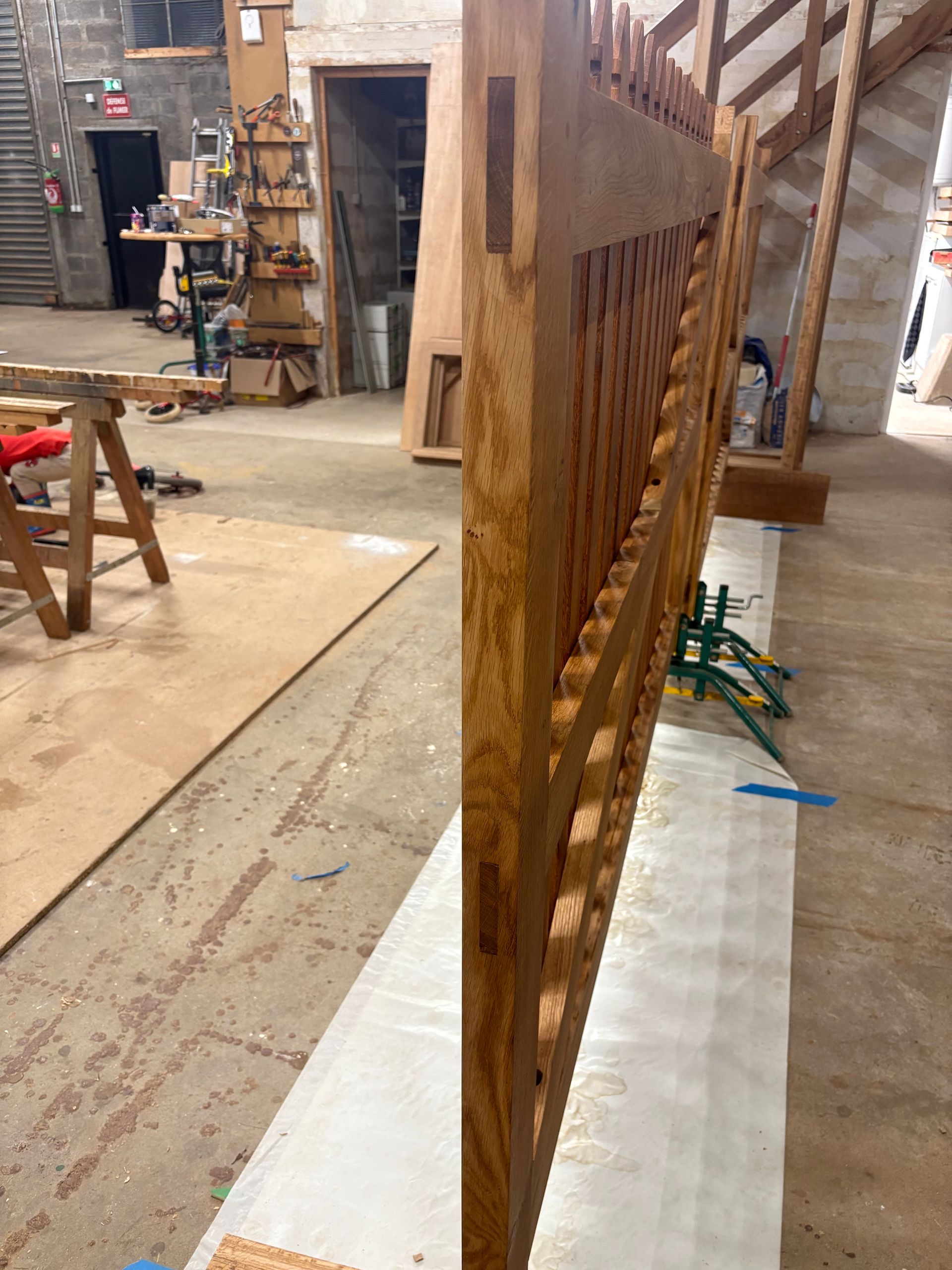 Panneau décoratif en bois posé à la verticale dans un atelier, avec des détails de treillis sculptés.