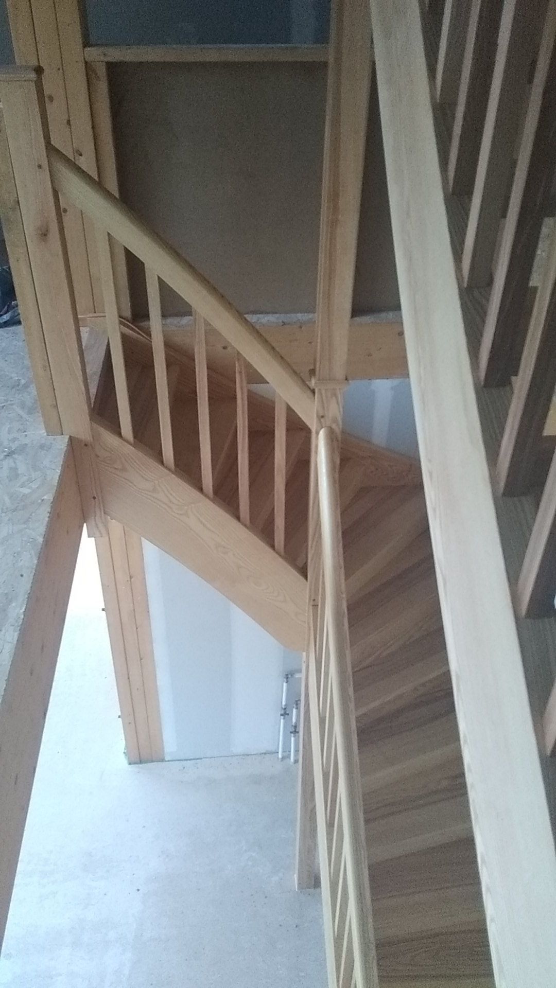 Escalier en bois avec rambardes dans un couloir intérieur étroit.