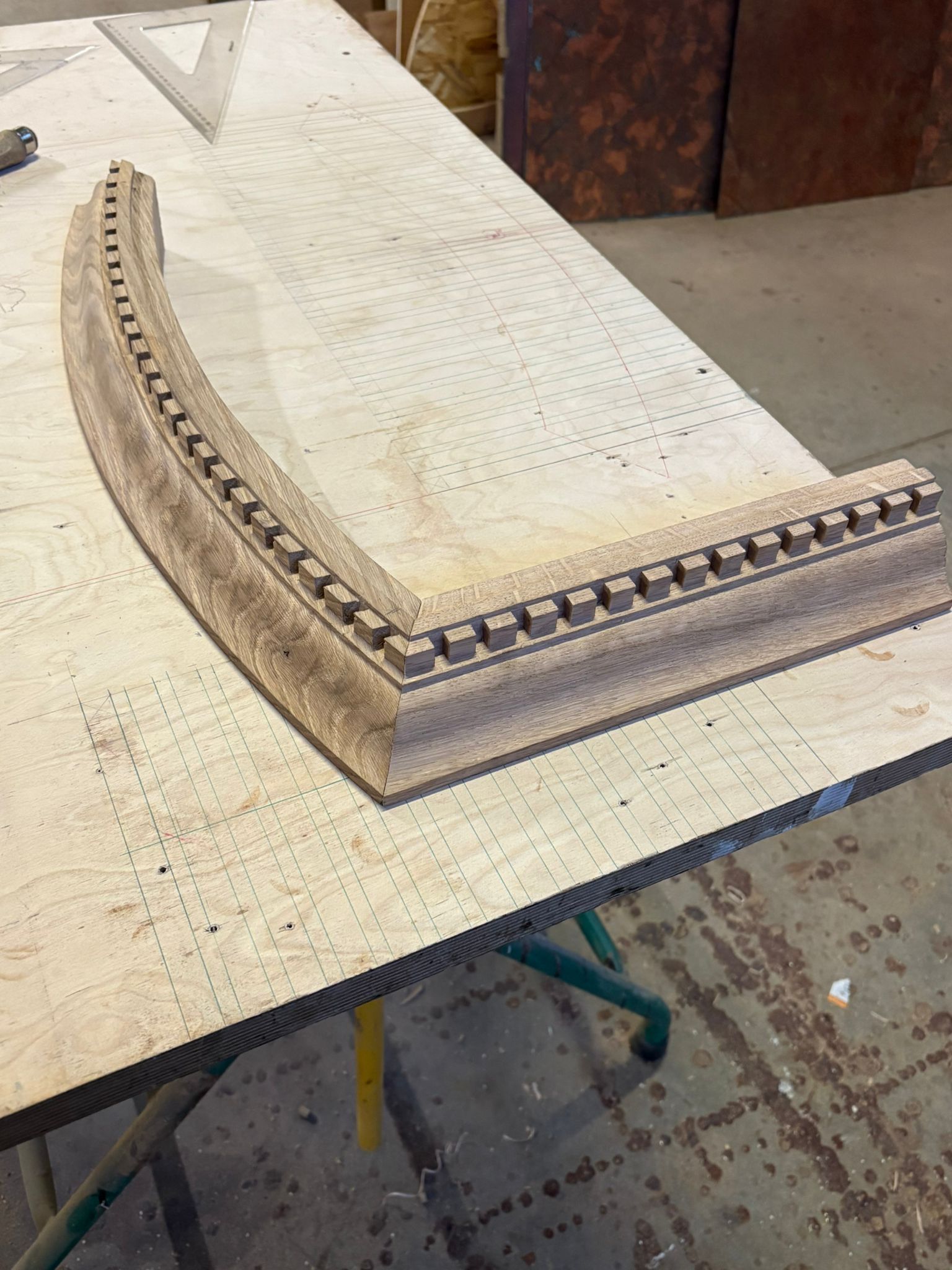 Moulure en bois courbée avec un bord à motifs, posée sur un établi dans un atelier.