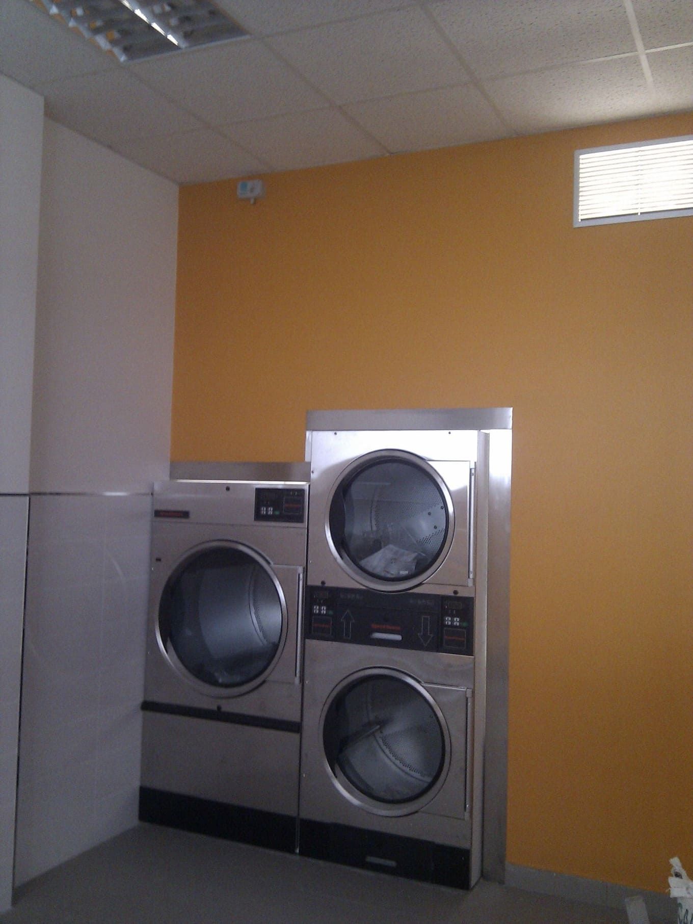 Una lavadora y una secadora están apiladas una encima de la otra en una lavandería automática.