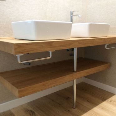 Hay dos lavabos sobre un estante de madera en un baño.