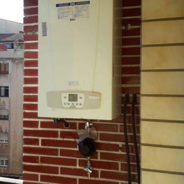 Una caldera está montada en una pared de ladrillos.