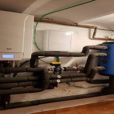 Una habitación con muchas tuberías y una caldera en la pared.